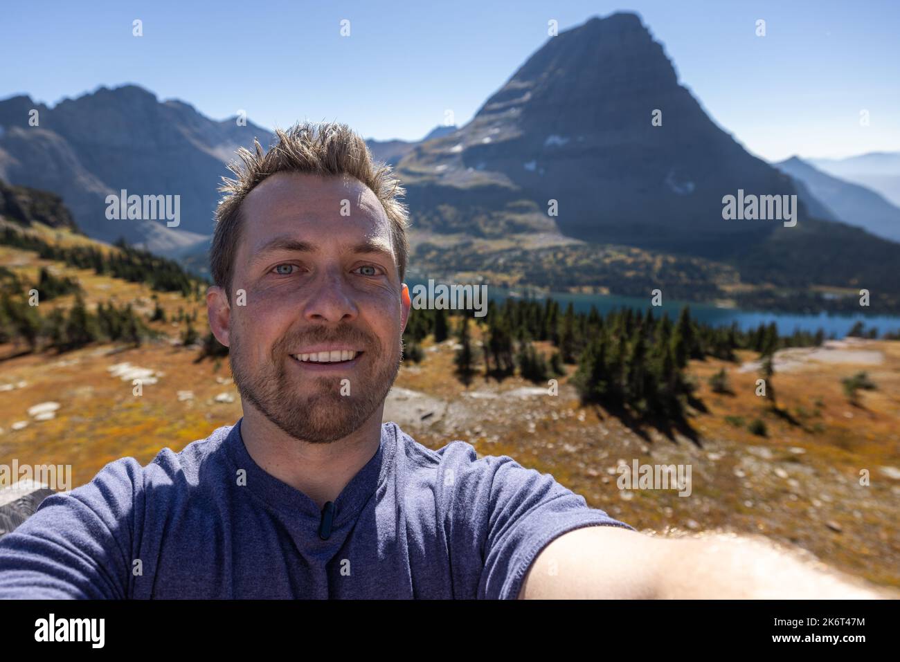 young man taking a selfie with the iconic hidden lake in te background, Glacier National Park. Stock Photo