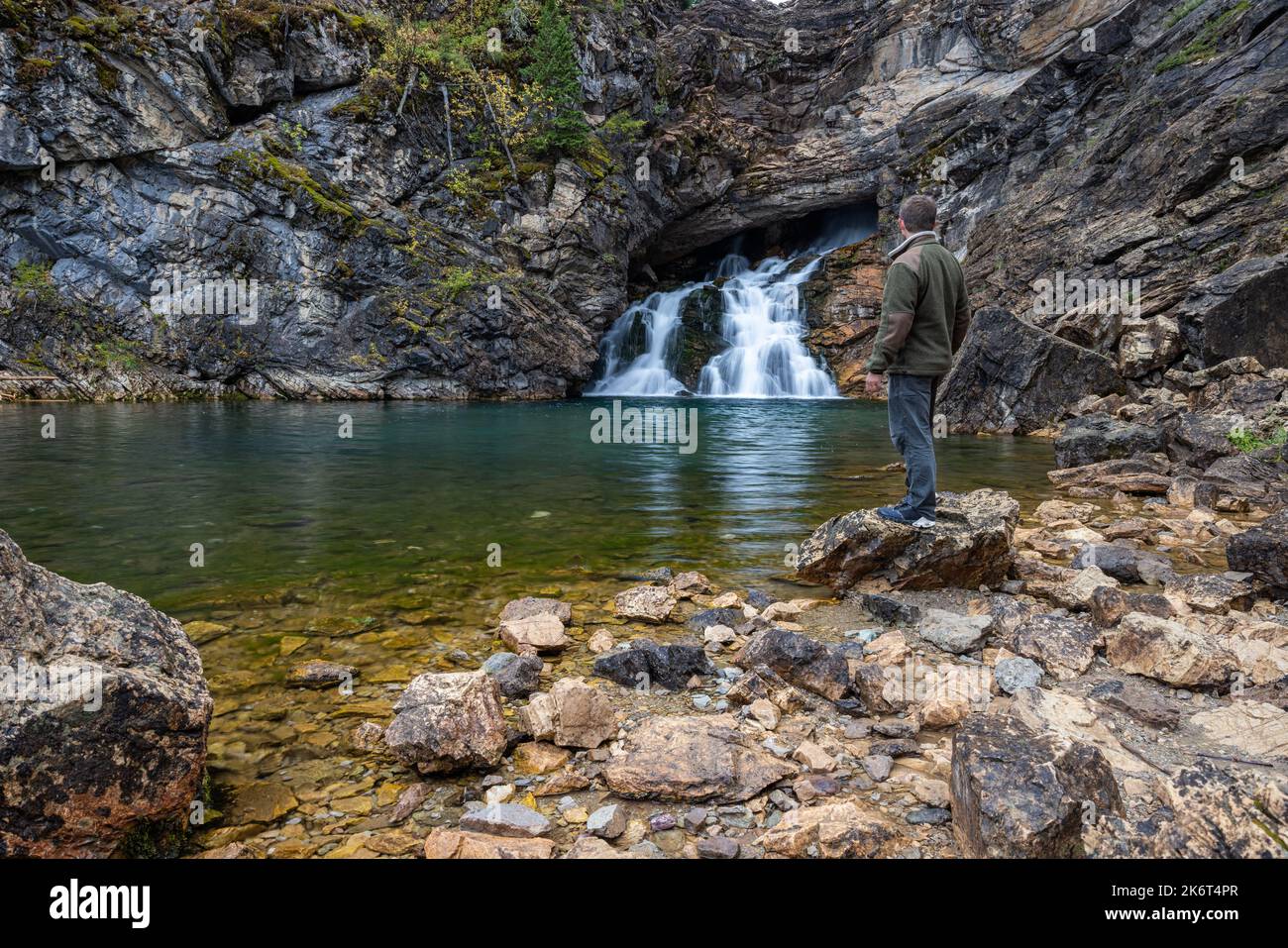 Man standing on the rocks viewing Running Eagle Falls in the Two Medicine section of Glacier National Park Stock Photo
