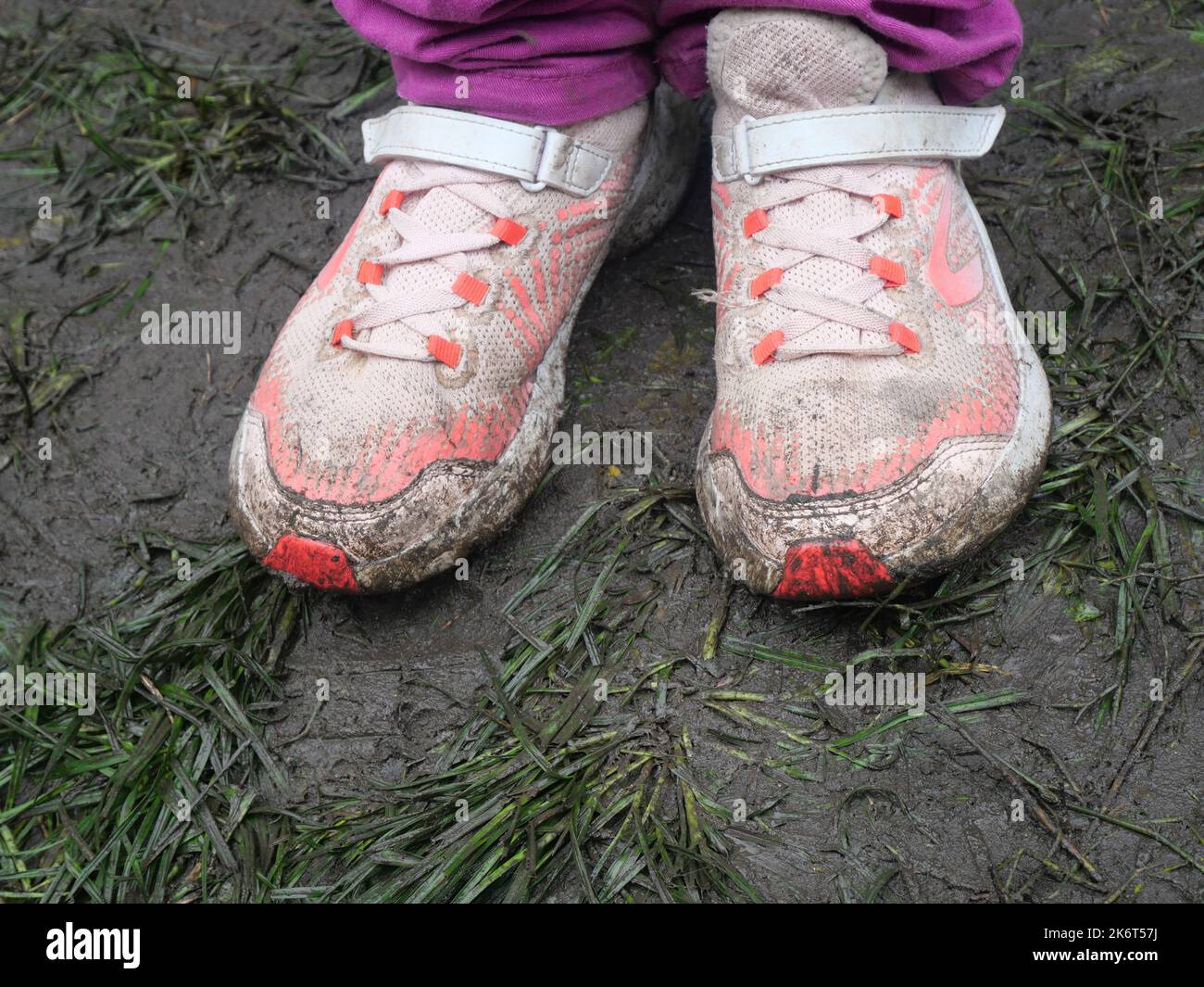 Dirty children shoes on a muddy ground. Shoes covered by mud, dirt road