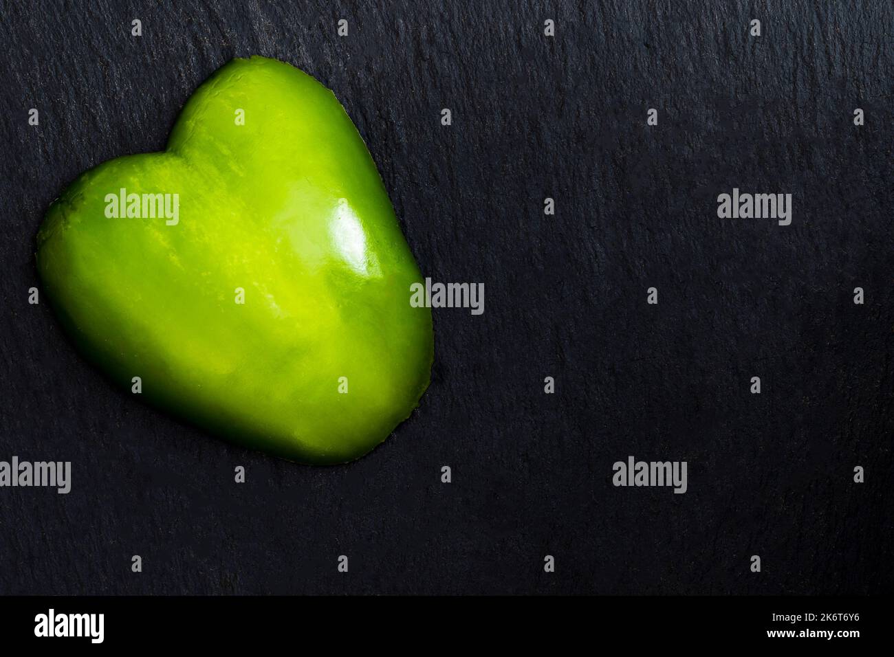 Heart-shaped pepper piece on a black slate plate Stock Photo