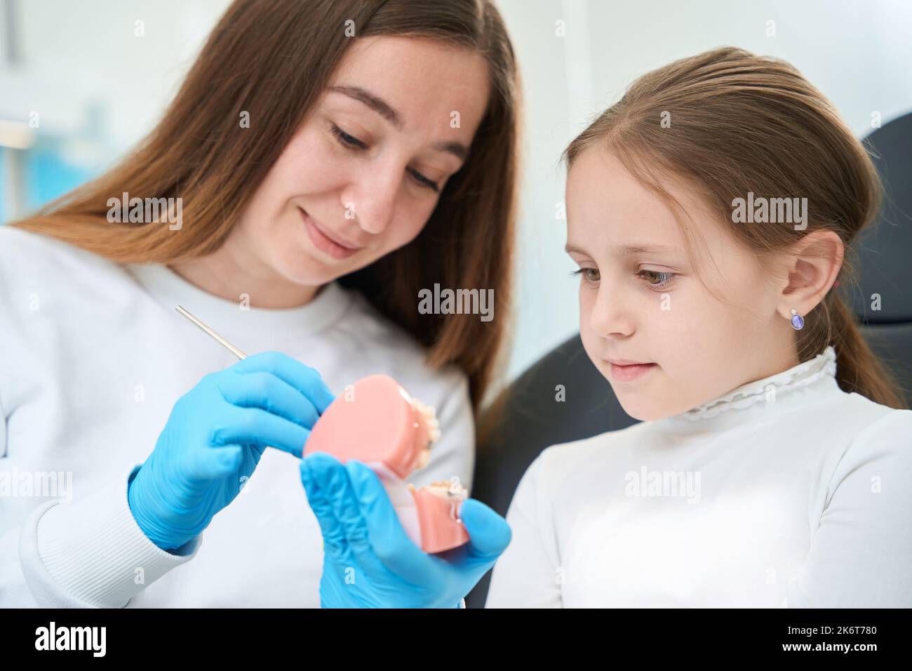 Pediatric dentist explaining teeth examination procedure to young