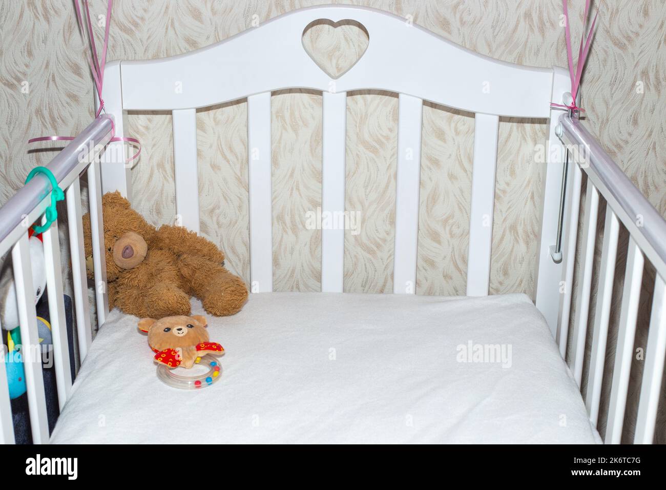 White crib with children's toys. A place to sleep for a newborn baby