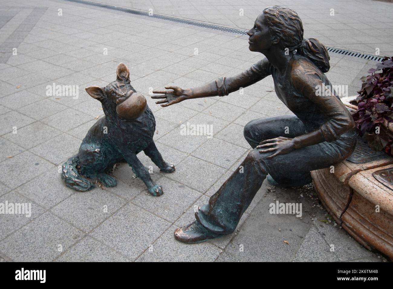 Lifesize bronze sculpture of a girl playing ball with her dog by