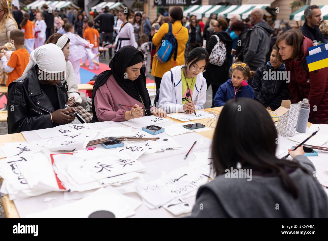 Ljubljana, Slovenia. 15th Oct, 2022. A teacher from the Confucius Institute in Ljubljana (3rd L) showcases Chinese calligraphy at a charity event in Ljubljana, Slovenia, Oct. 15, 2022. The Confucius Institute in Ljubljana on Saturday showcased Chinese culture at a charity event held in the capital of Slovenia. Visitors had the chance to taste Chinese tea, experience Chinese calligraphy, and put on Hanfu, traditional Chinese clothing, to take photos at the event, which aims at raising fund for Slovenian children in need. Credit: Zeljko Stevanic/Xinhua/Alamy Live News Stock Photo