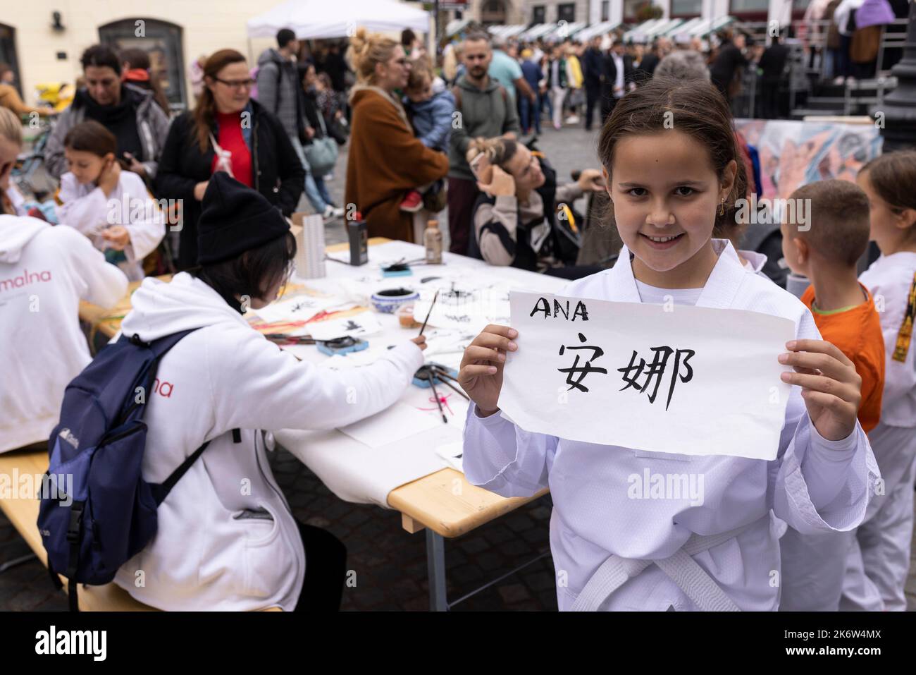 Ljubljana, Slovenia. 15th Oct, 2022. A girl shows her name in Chinese calligraphy at a charity event in Ljubljana, Slovenia, Oct. 15, 2022. The Confucius Institute in Ljubljana on Saturday showcased Chinese culture at a charity event held in the capital of Slovenia. Visitors had the chance to taste Chinese tea, experience Chinese calligraphy, and put on Hanfu, traditional Chinese clothing, to take photos at the event, which aims at raising fund for Slovenian children in need. Credit: Zeljko Stevanic/Xinhua/Alamy Live News Stock Photo