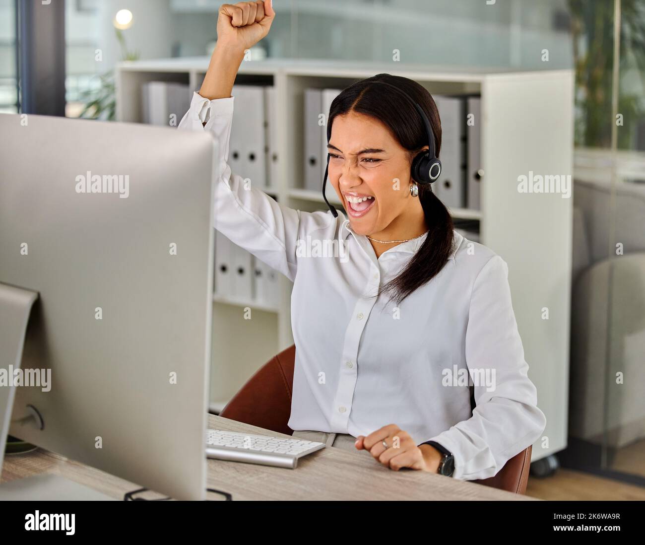 Lady luck is smiling upon me. a young businesswoman cheering while working in a call center. Stock Photo