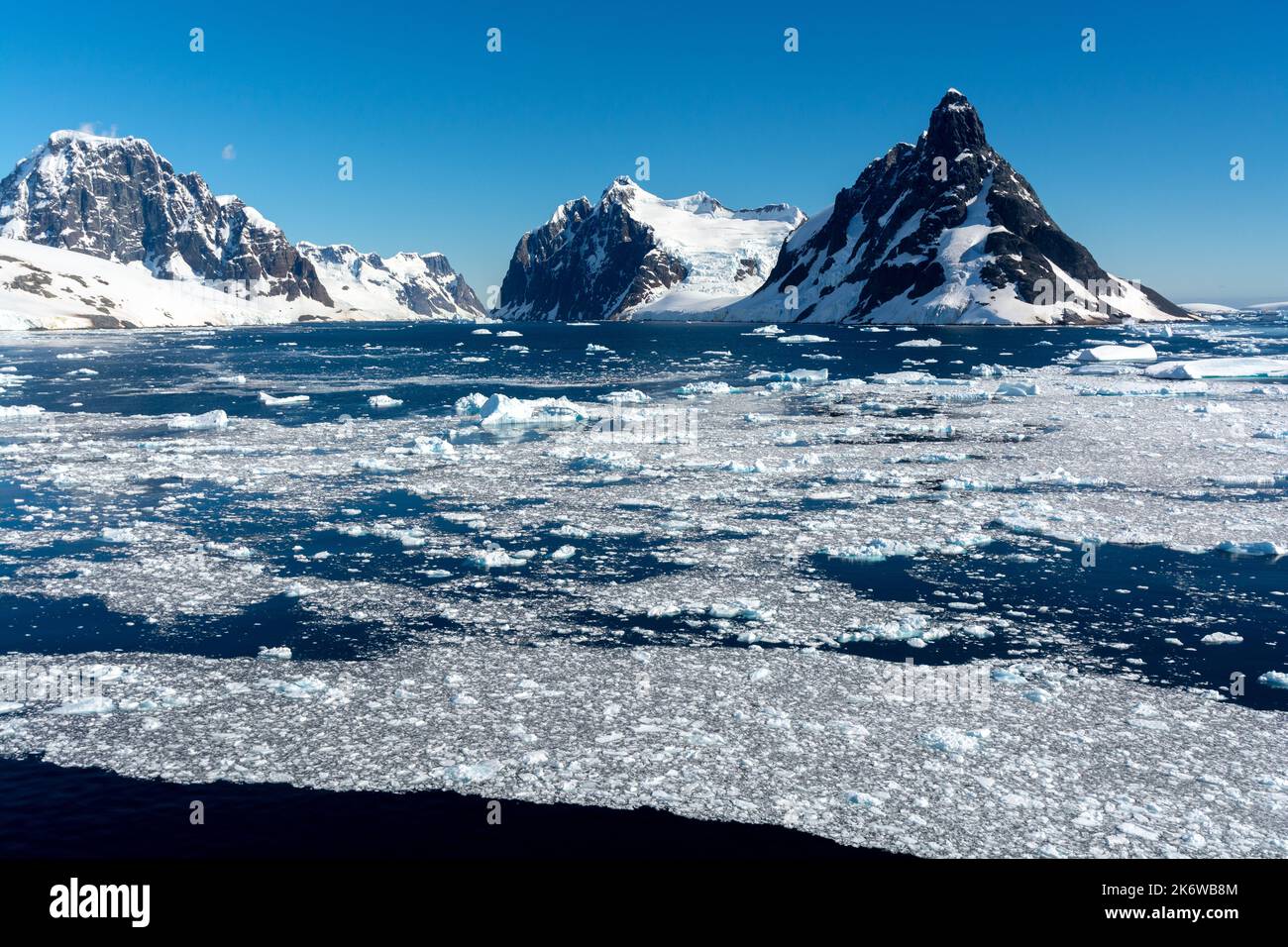 brash ice floating on waters of northern approach to lemaire channel (kodak gap, kodak alley) with booth island and mt. lacroix on right and humphries Stock Photo