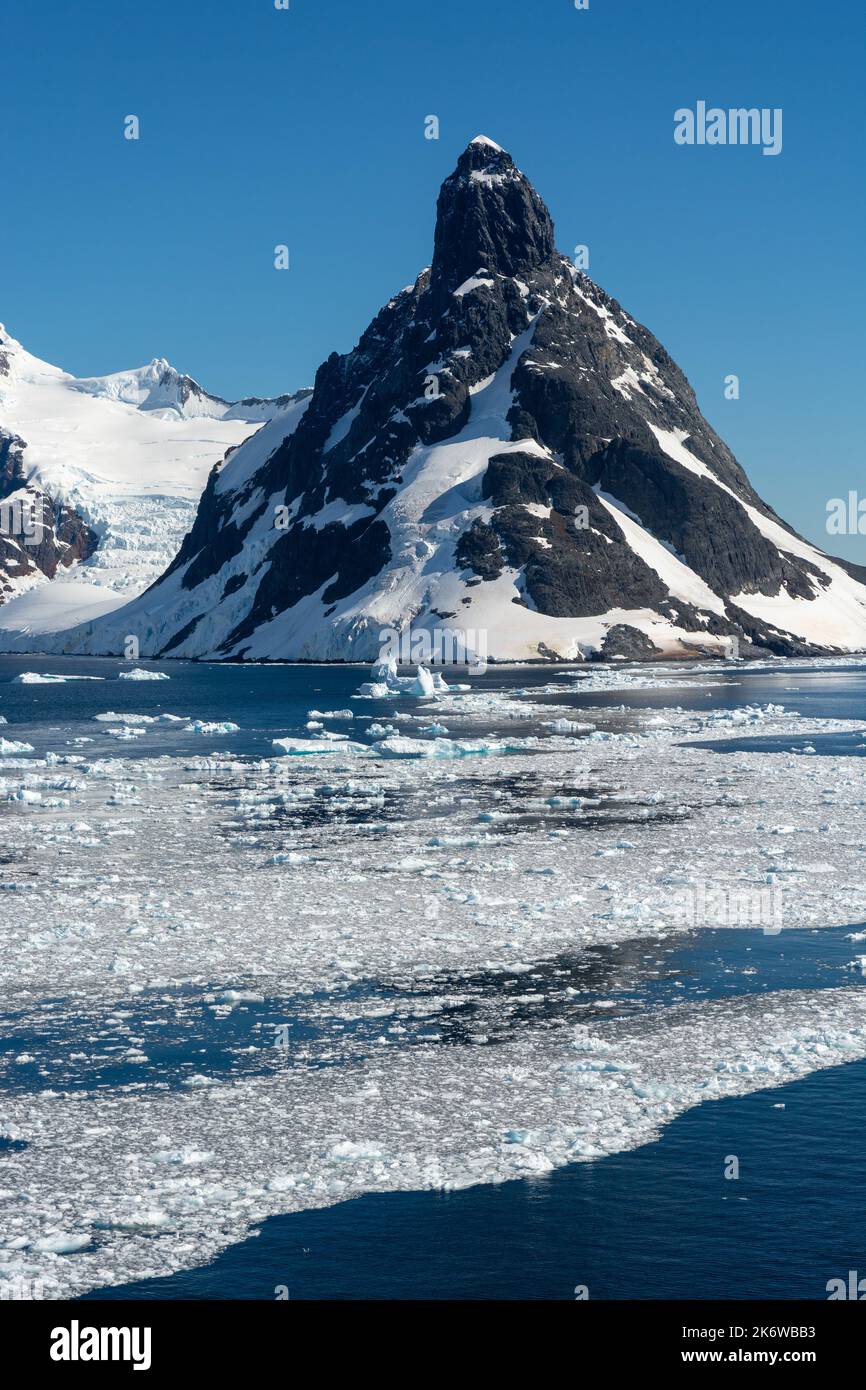 brash ice floating on waters of northern approach to lemaire channel (kodak gap, kodak alley) with booth island and mt. lacroix in background. wilhelm Stock Photo