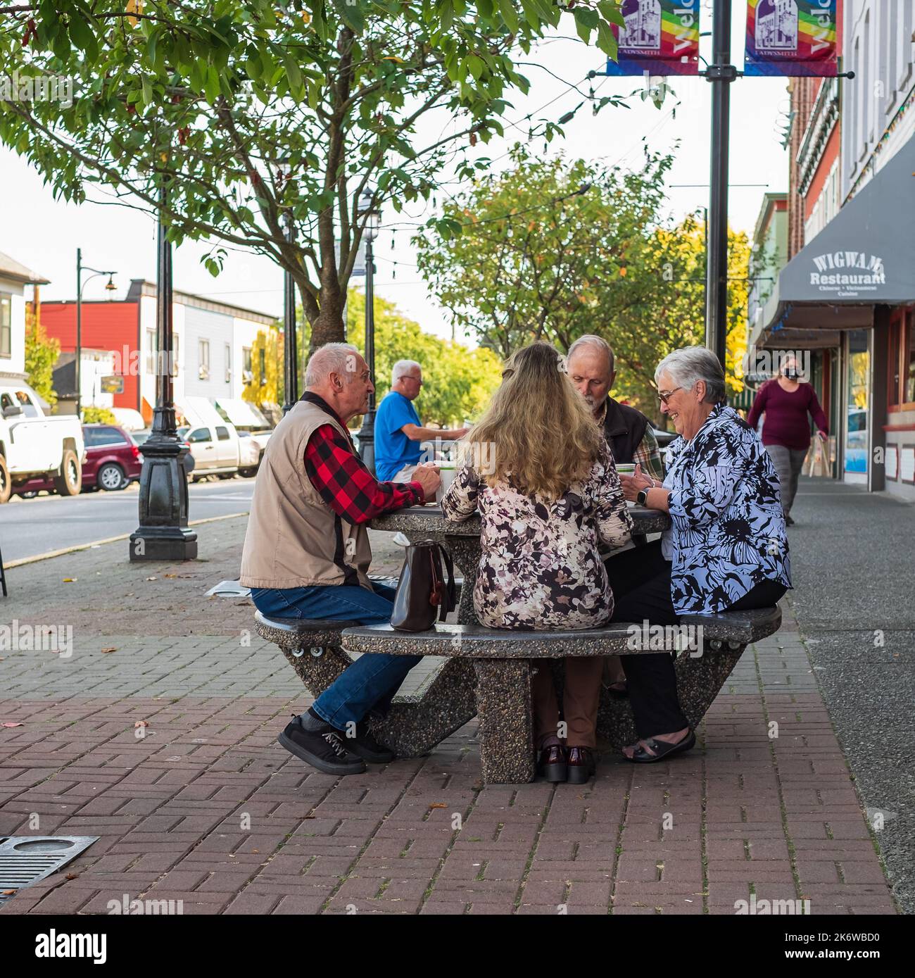 Active retirement, old people and seniors free time, group of four elderly men having fun and playing cards game at park. Street photo, selective focu Stock Photo