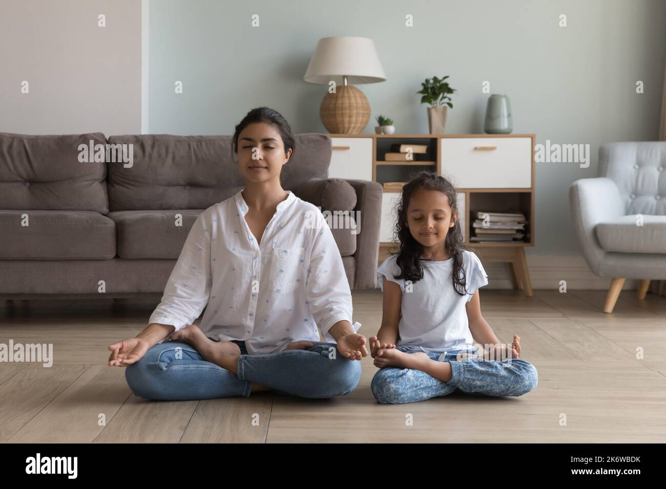 Silent Indian woman and preschooler daughter meditating seated indoors Stock Photo