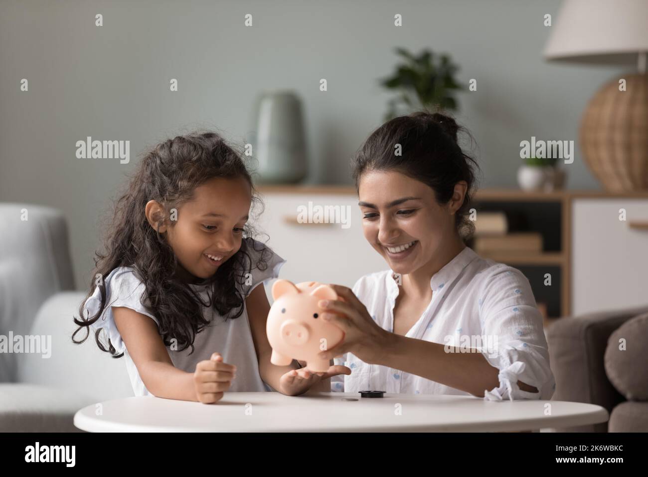 Indian woman and daughter take out money from piggybank Stock Photo