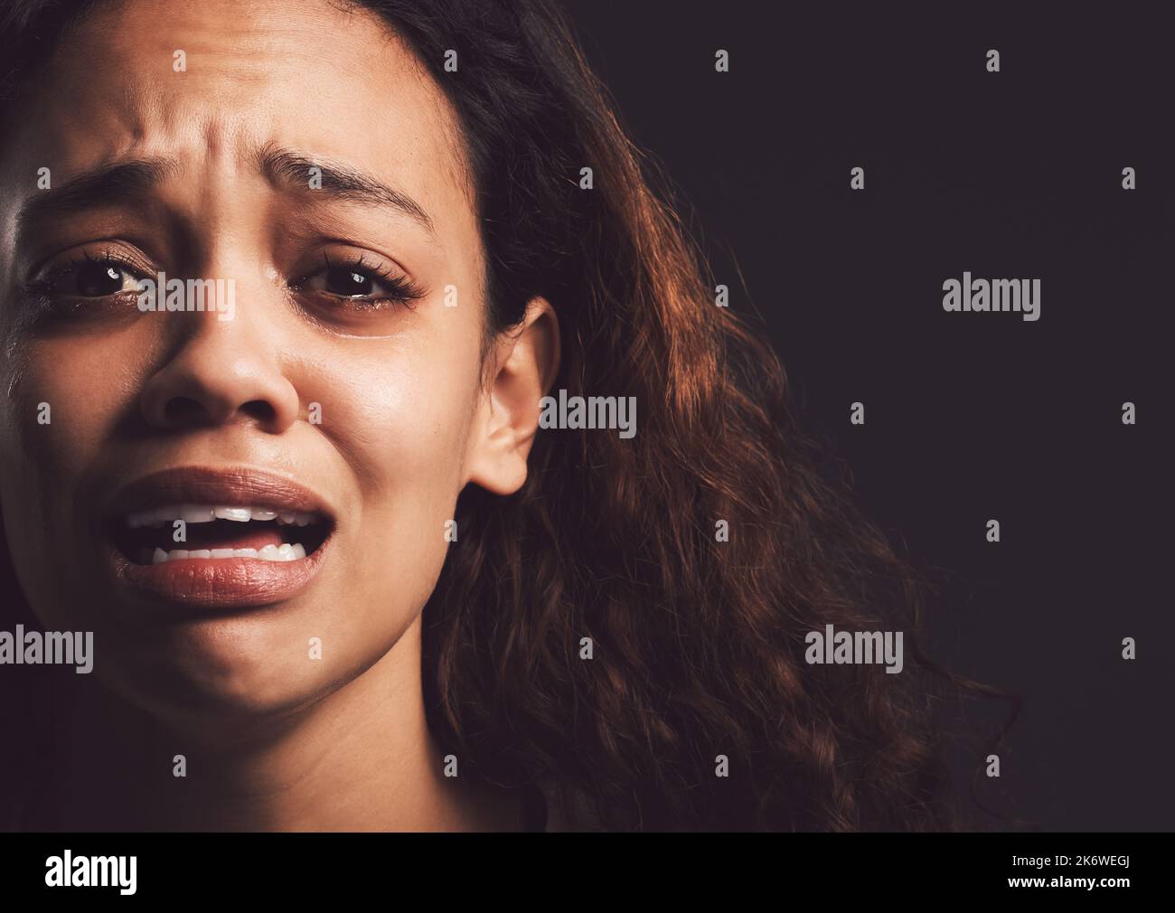 My dark days made me strong. a young woman crying against a black background. Stock Photo