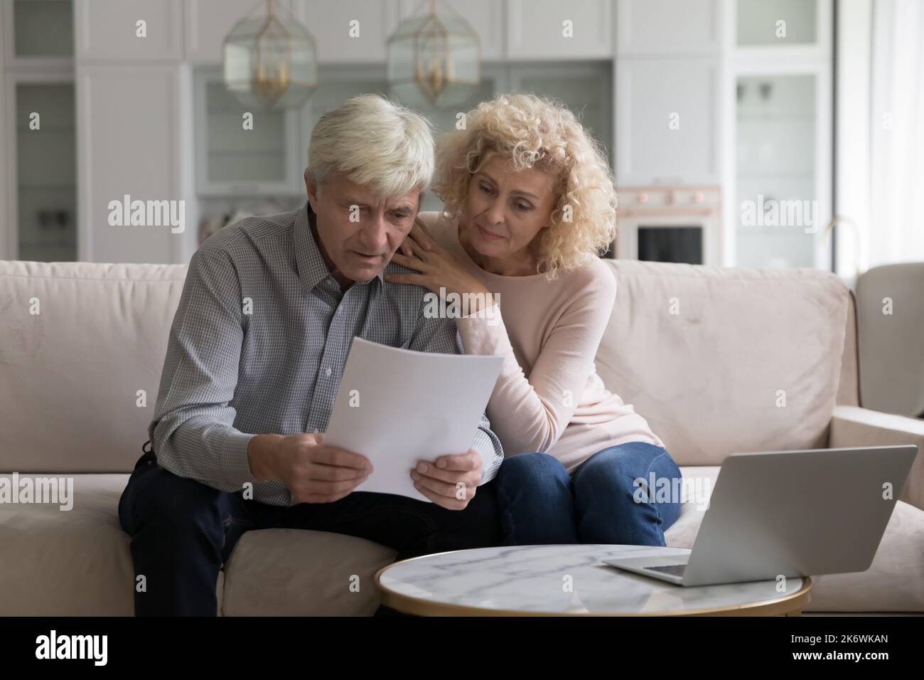 Concerned older couple read received formal notification from bank Stock Photo