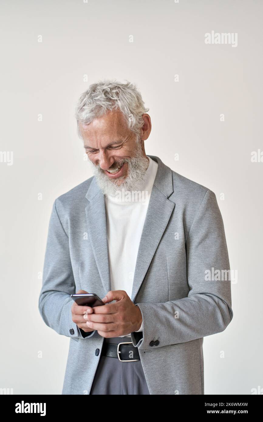 Happy old senior businessman using smartphone standing isolated on white. Stock Photo