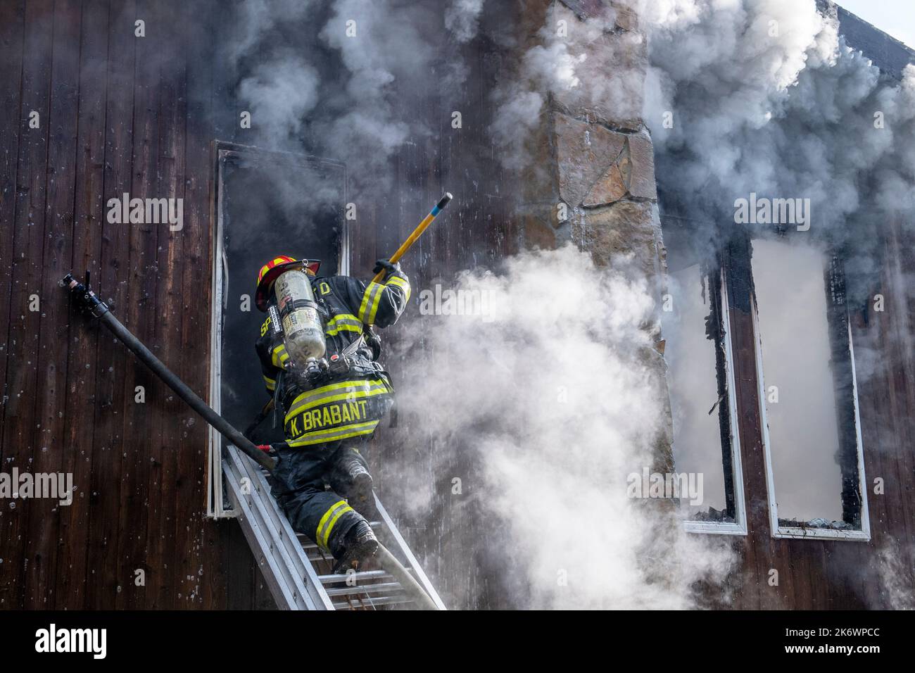A Springs firefighter uses a hook to sound the floor before crawling into a window from a ground ladder as members of the Springs Fire Department, alo Stock Photo