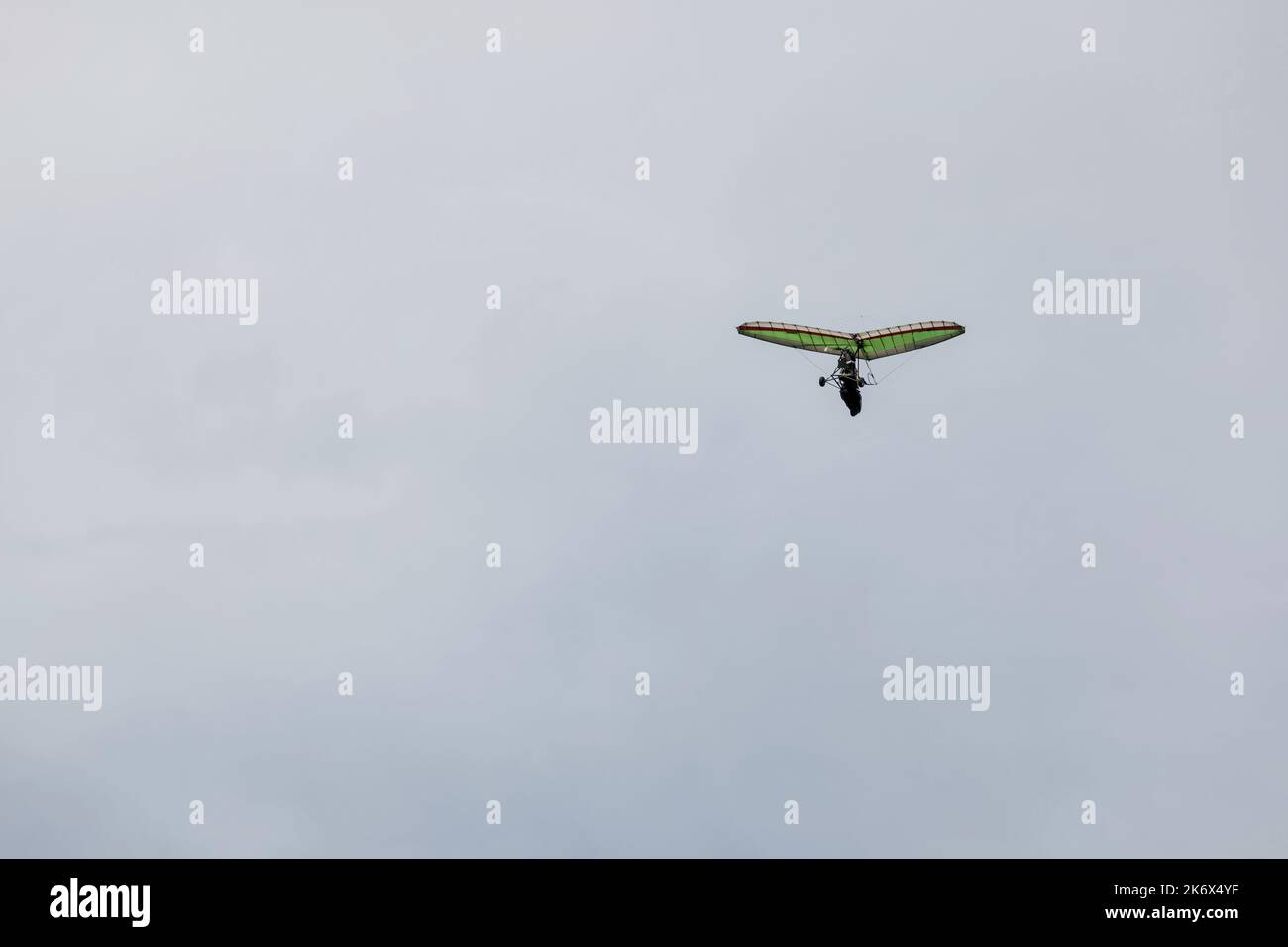 Powered hang glider flying in blue sky. Motorized hang glider