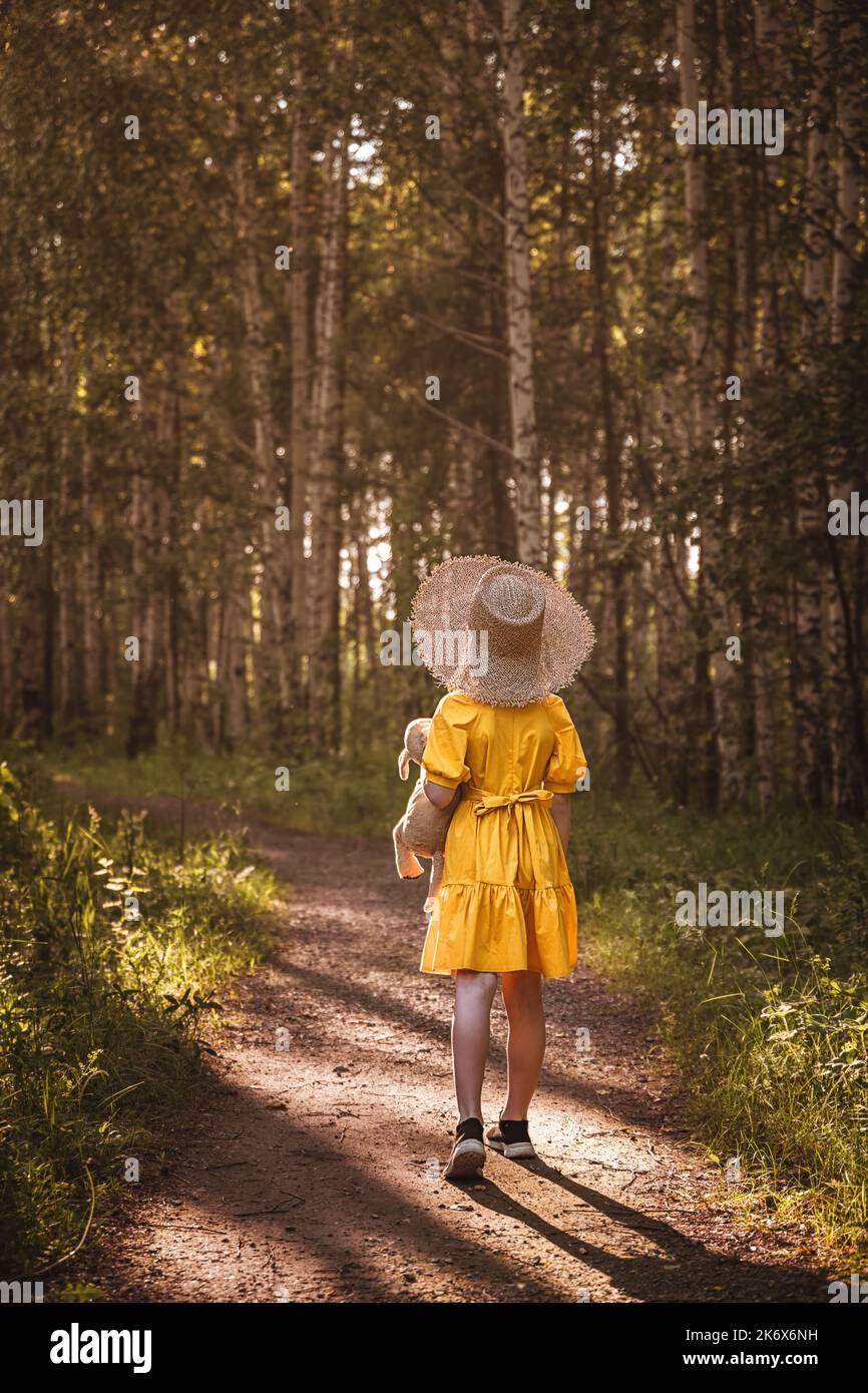 cute little girl in a yellow dress and straw hat walking through the ...