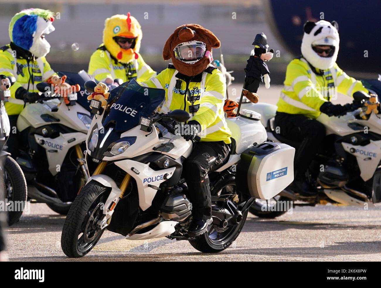 Police officers wearing decorative helmets escort buses carrying