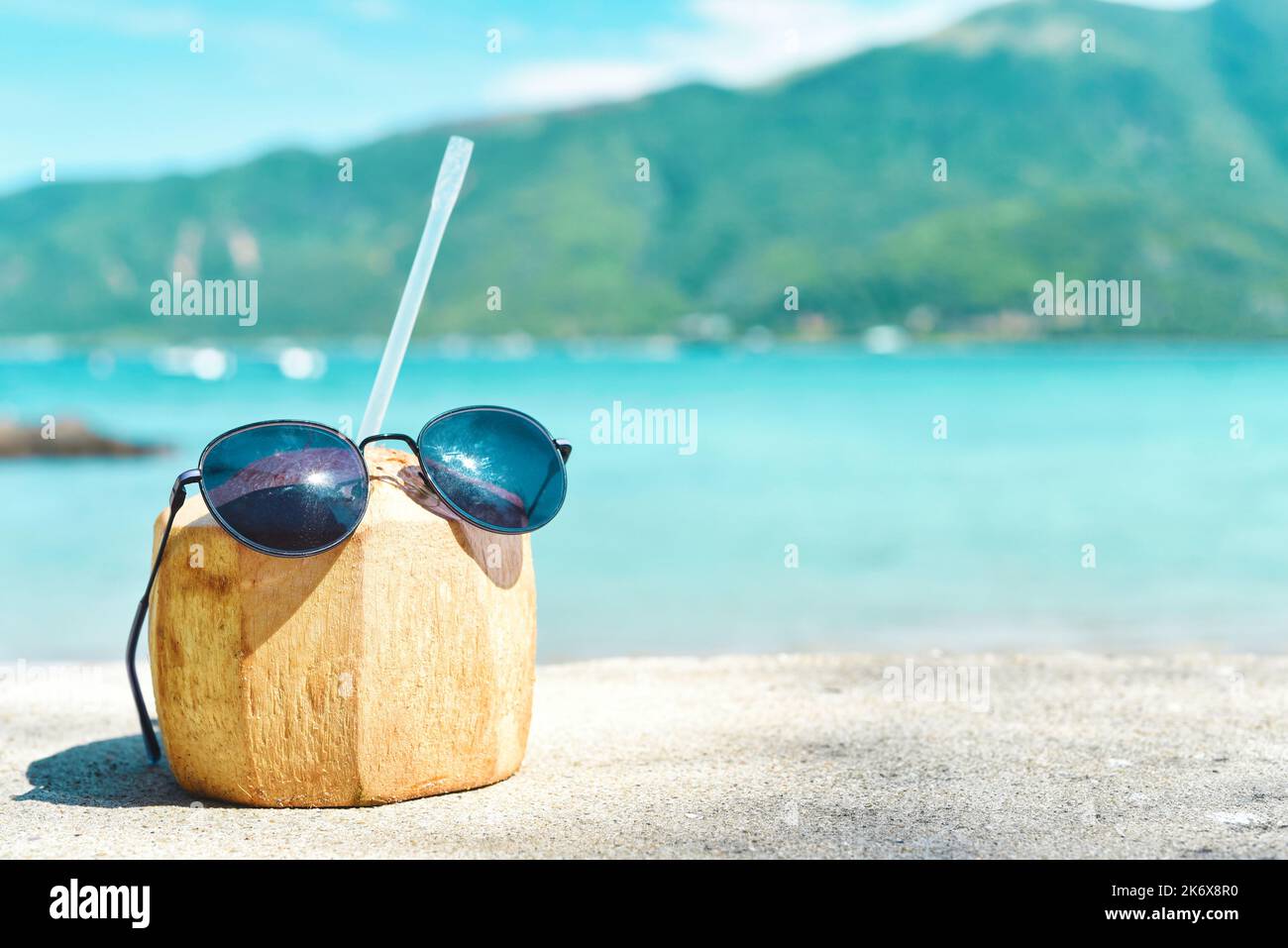 Coconut drink with straw and sunglasses on tropical beach background ...