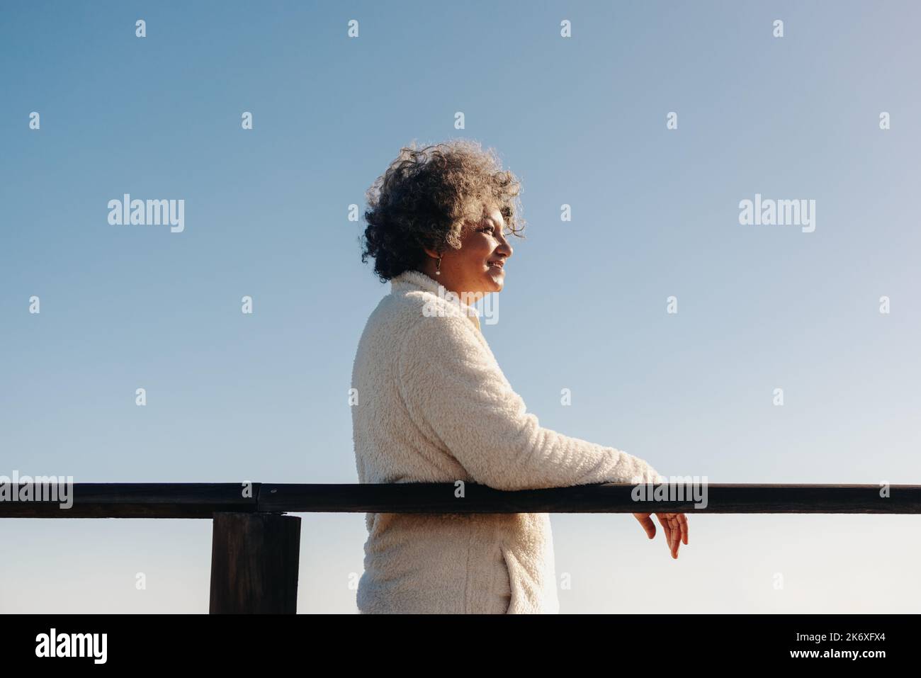 Mature woman looking at a view of the ocean while standing on a ...