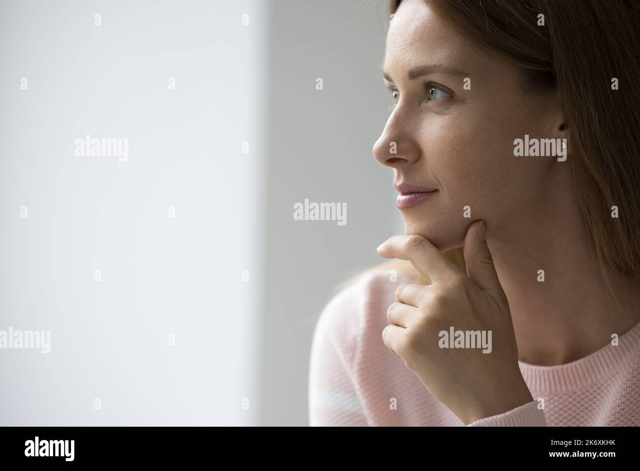 Attractive young 30s woman looks pensive staring into distance Stock Photo