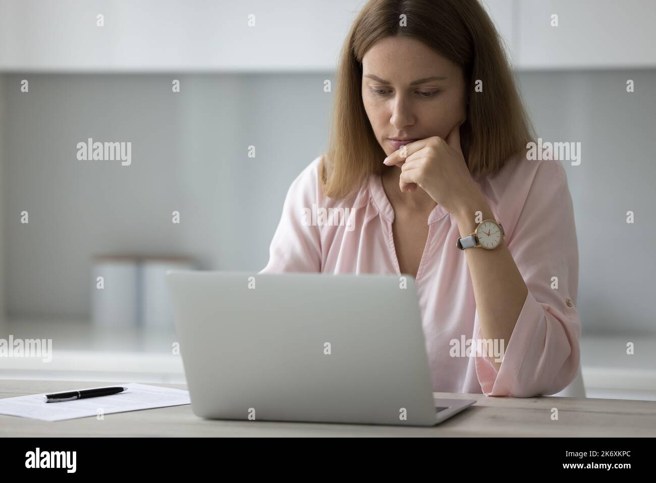 Serious pensive freelancer woman working on laptop Stock Photo