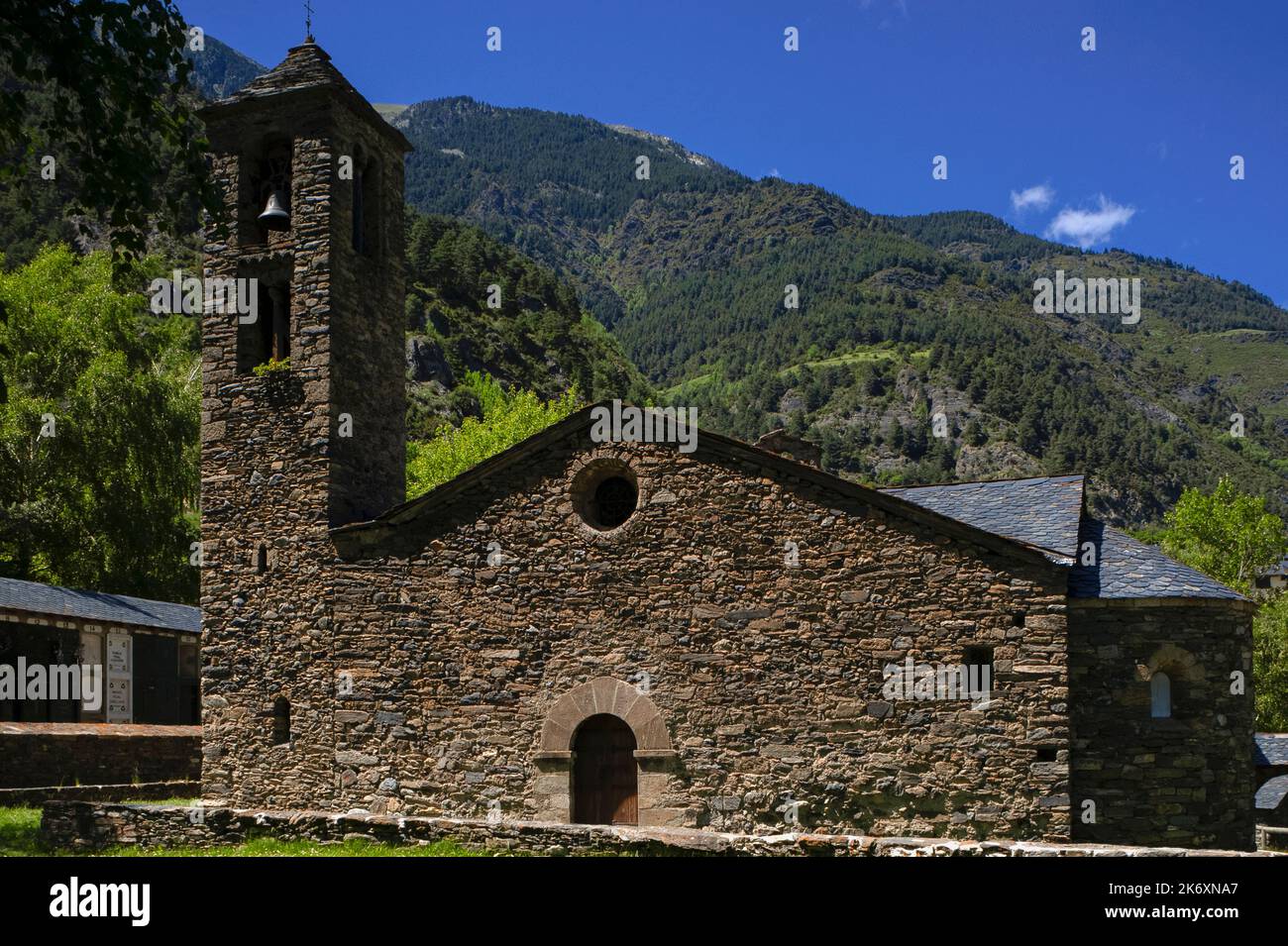 Església de Sant Martí (Church of Saint Martin), a medieval Romanesque church at La Cortinada in the Ordino Valley in Andorra. The church was built in the 1000s and 1100s AD and stands amid rugged but well-wooded slopes in the eastern Pyrenees.  It has rubble walls, a two-storey bell tower and a fish scale roof. Stock Photo