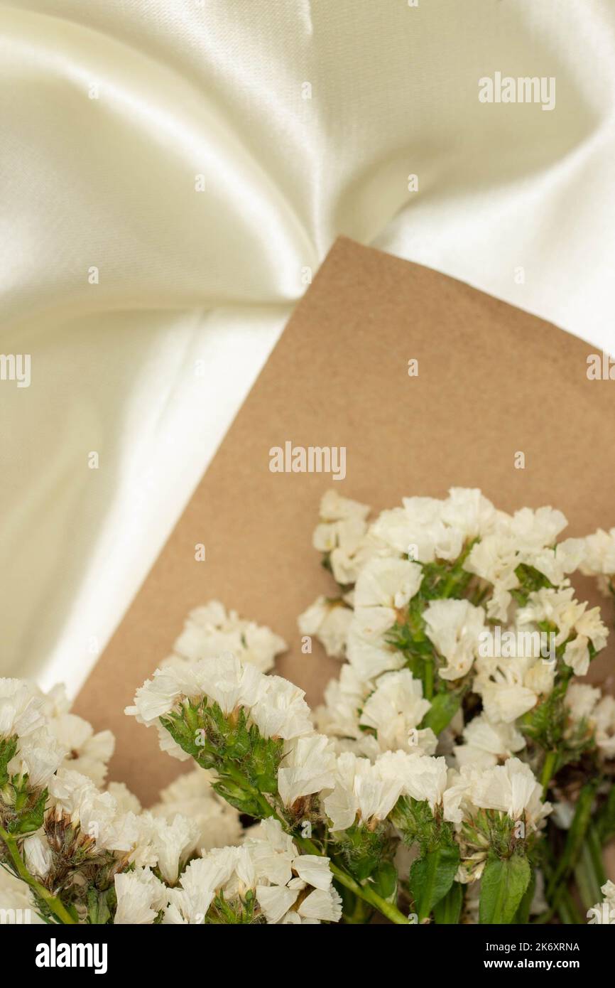 Beautiful flower concept, Bouquet of white blooming statice with brown paper on white cloth. Stock Photo