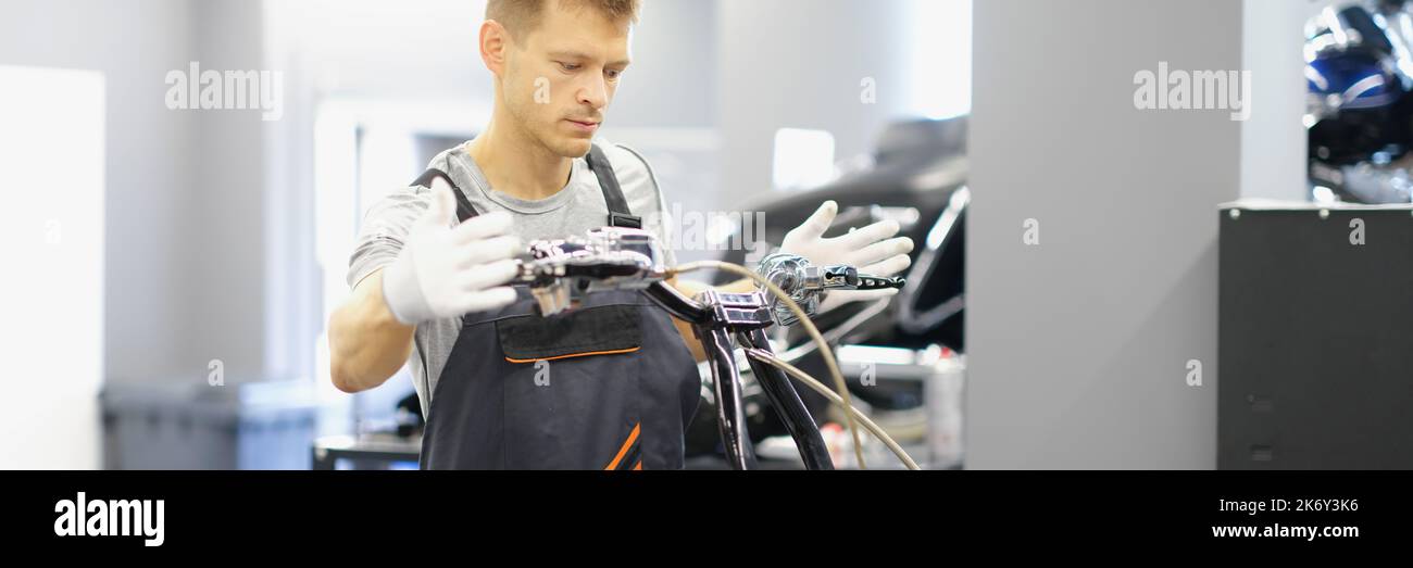 A man mechanic repairs the steering wheel of a motorcycle Stock Photo