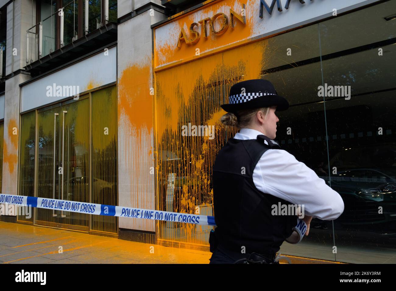 London, UK. 16 OCT, 2022. Just Stop Oil activists covered the Aston Martin showroom in Park Lane with orange paint and blocked the road. Members of the public drag an activists who are blocking the road. Police officers detain an activist after paint was thrown over a car showroom window. Credit: Joao Daniel Pereira/Alamy Live News Stock Photo