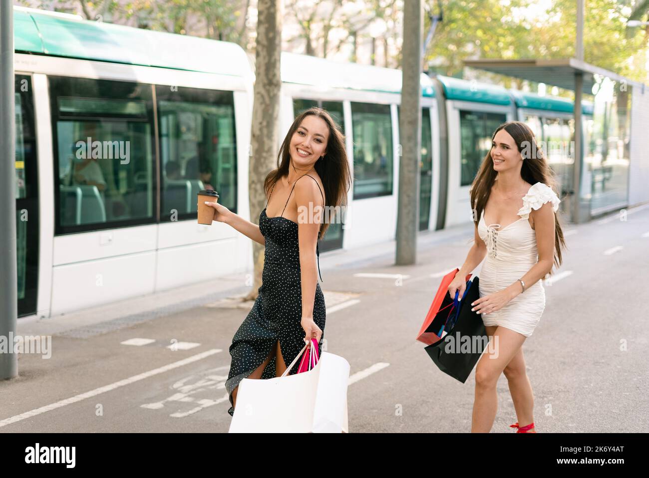 Cheerful female shoppers walking towards tram Stock Photo