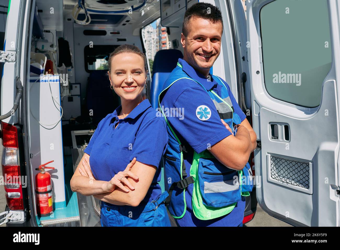 Ambulance medical staff. Portrait of paramedics team standing near their ambulance vehicle with crossed arms and looking at camera Stock Photo