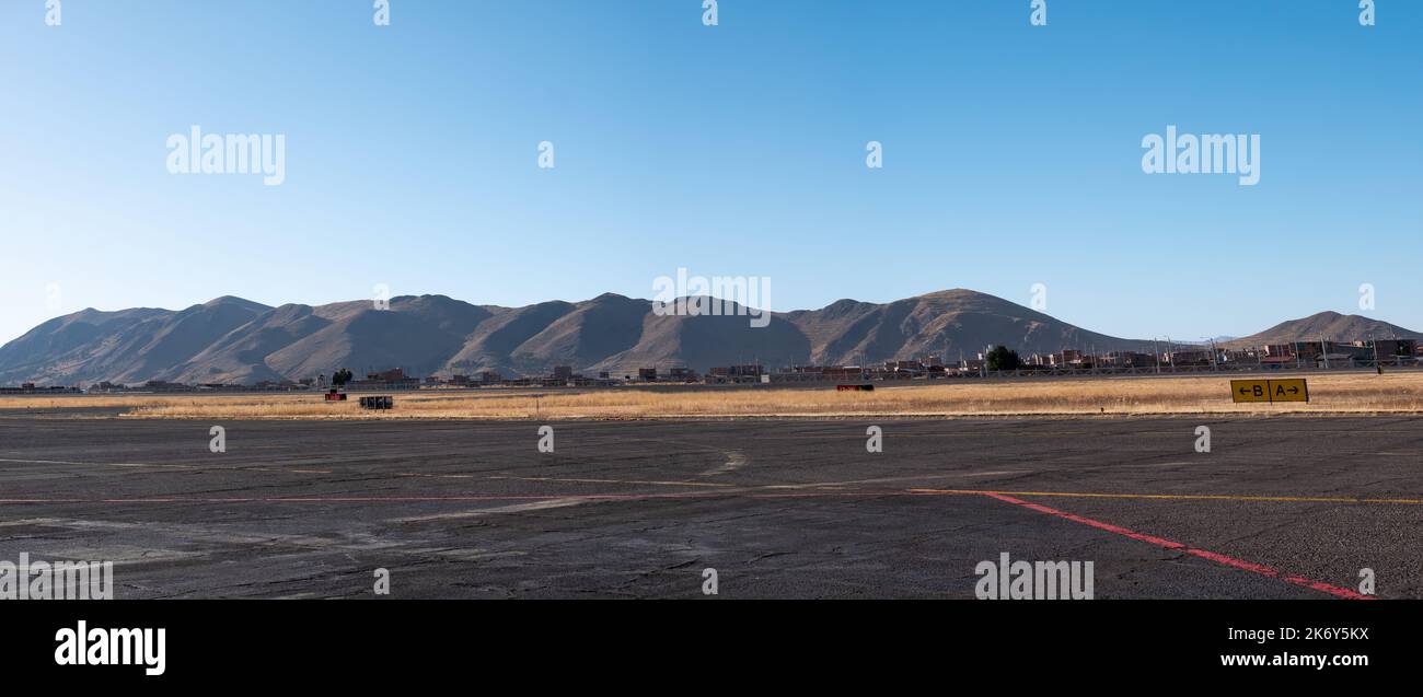 Airstrip with a View of the Mountains, the Dry and Yellow Soil in Contrast to a Beautiful Clear Blue Sky Stock Photo