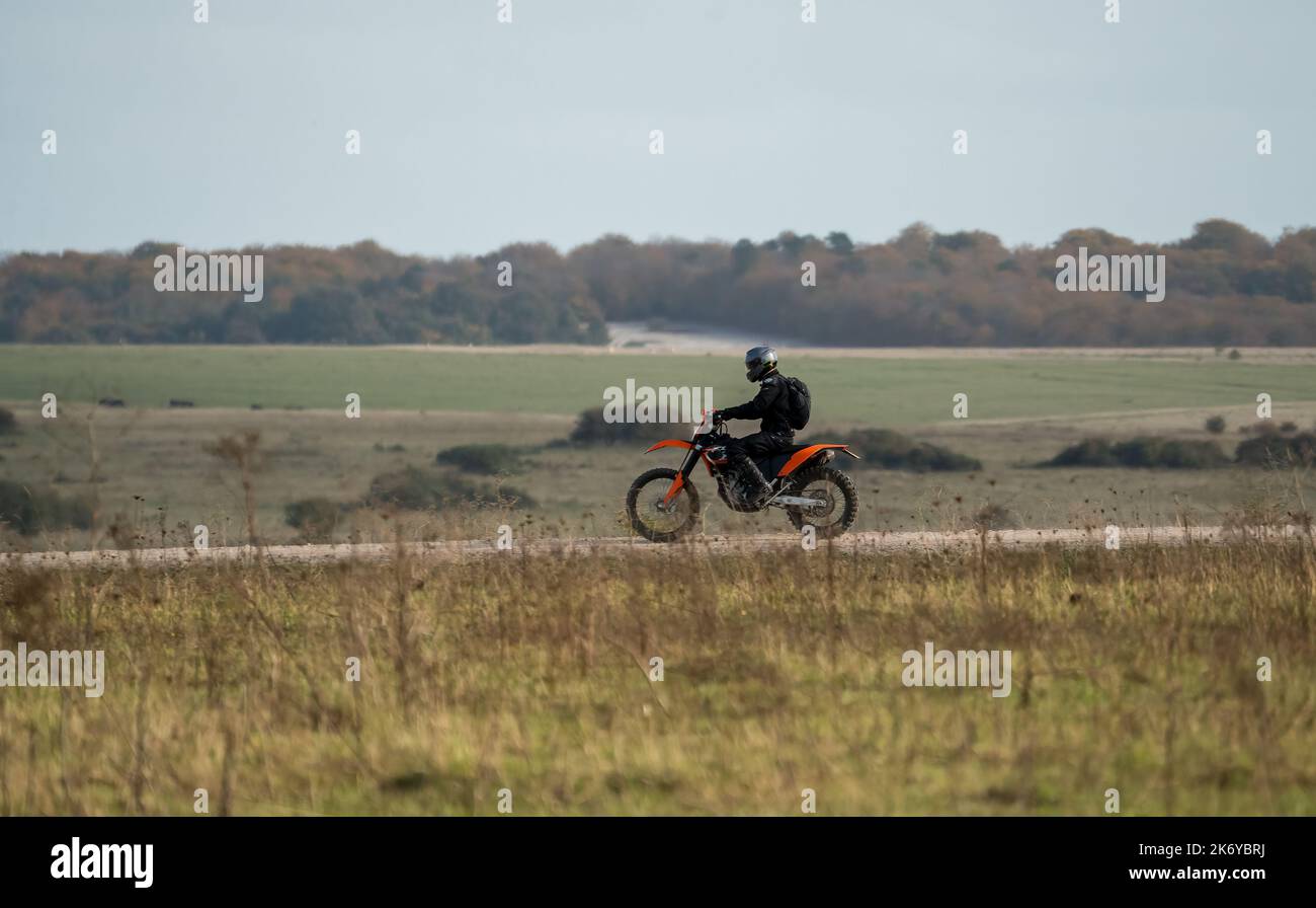 a motor cyclist (biker) riding their offroad motorbike along a stone