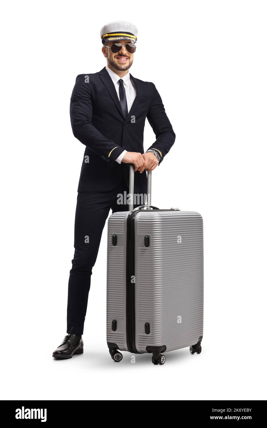 Young pilot in a uniform standing and holding a suitcase with wheels isolated on white background Stock Photo