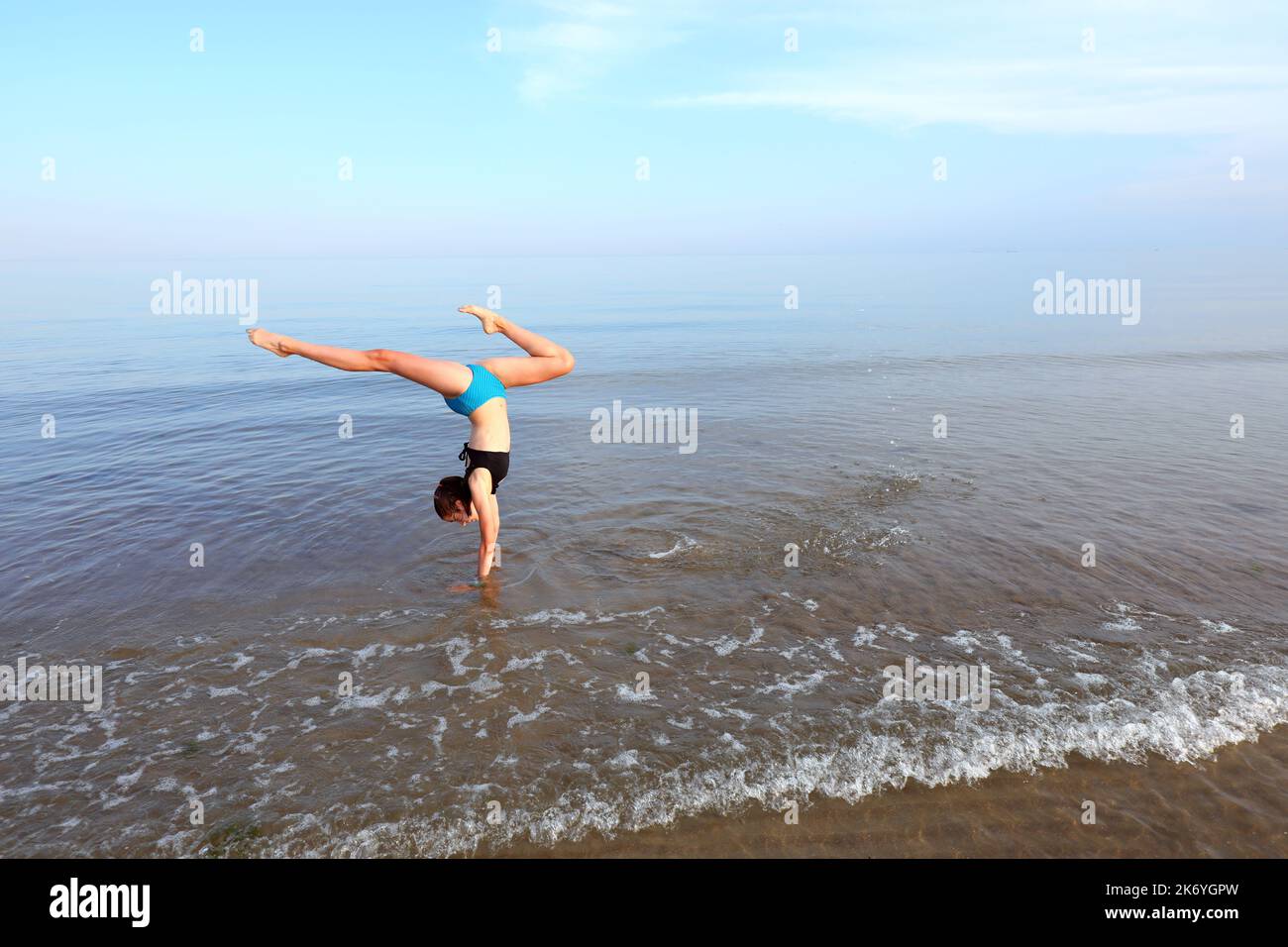 young girl performs gymnastic exercises with her head upside down on