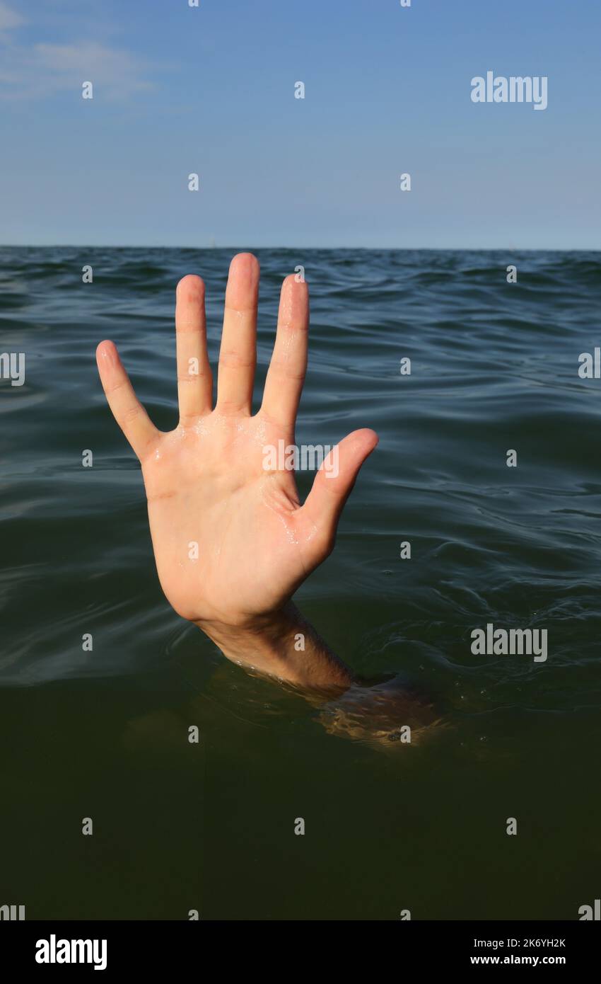 hand of the person with five fingers in the middle of the sea about to drown Stock Photo