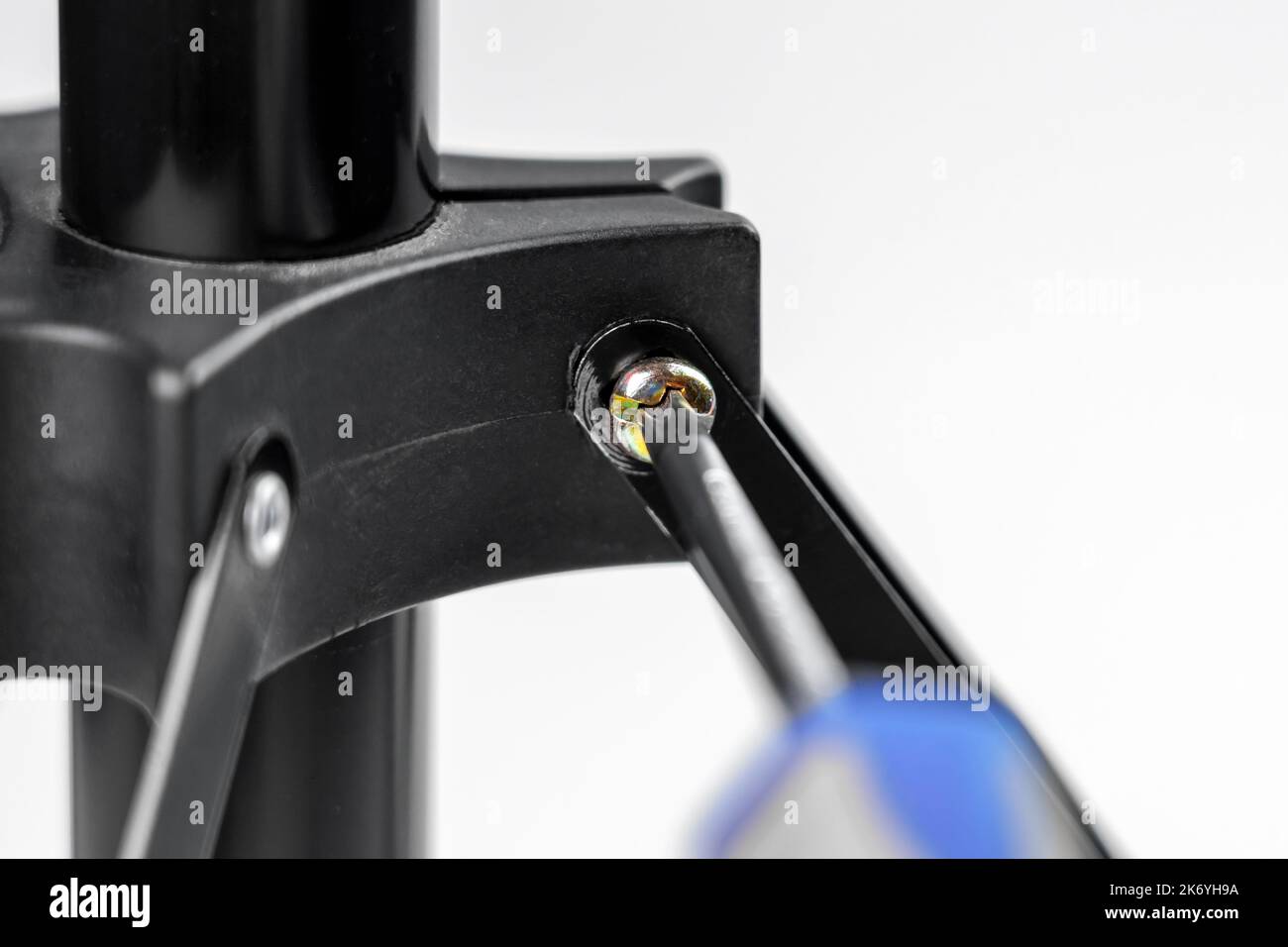 Screwdriver in the hand of a repairman tightens a galvanized screw close-up Stock Photo