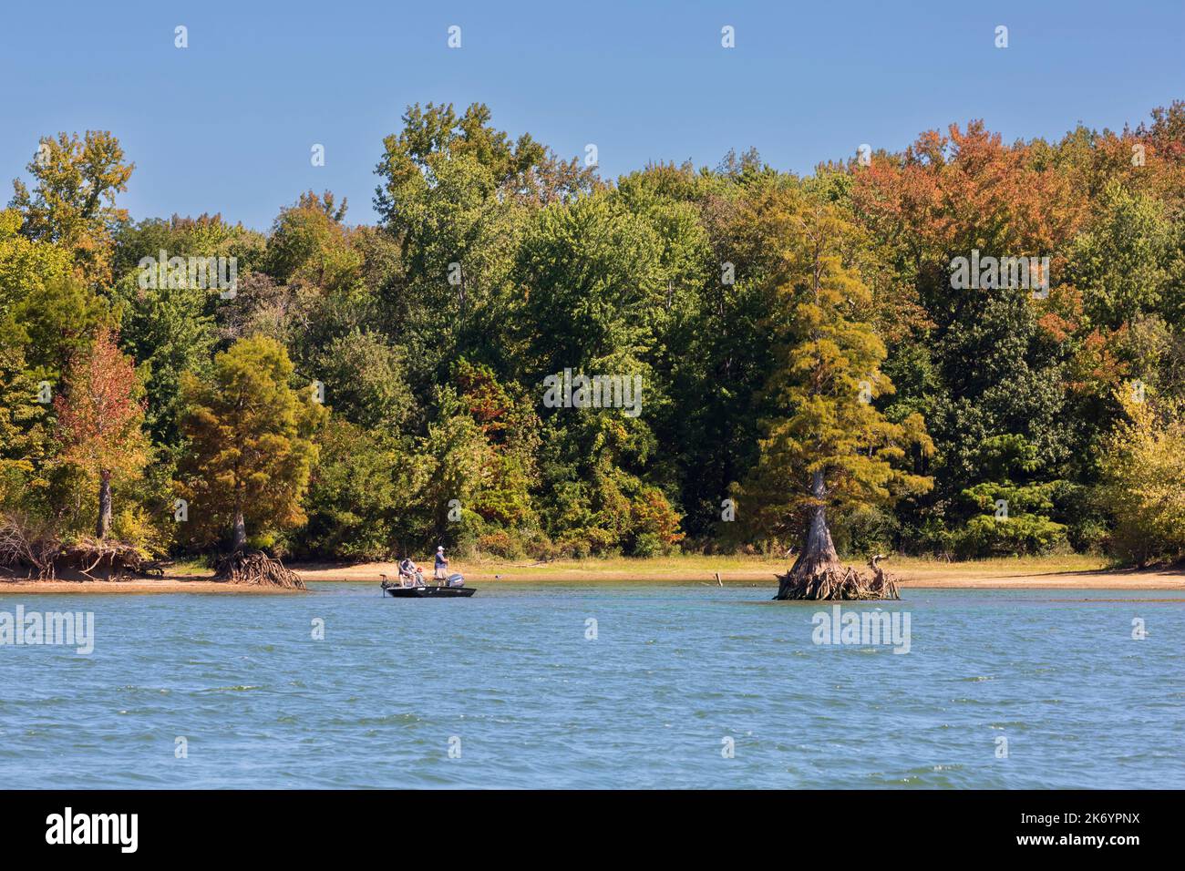 Three men fish from a small boat on Kentucky Lake in early autumn. Leaves are beginning to change colour at the beginning of October. Stock Photo