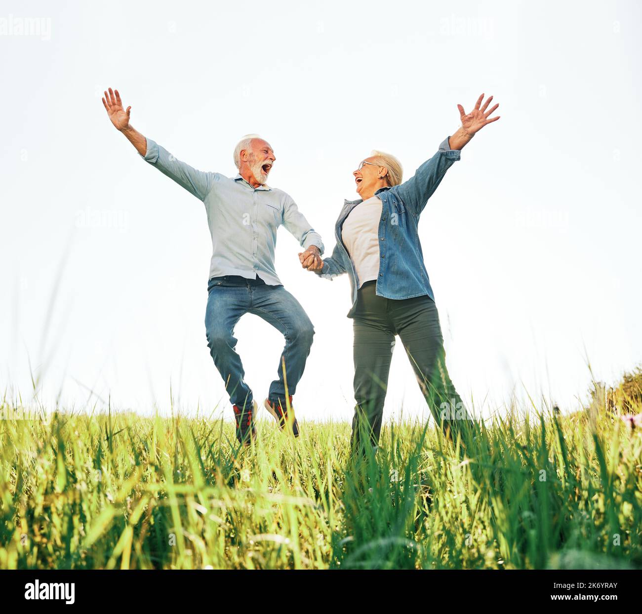 woman man outdoor senior couple happy lifestyle retirement together love jumping fun nature mature Stock Photo