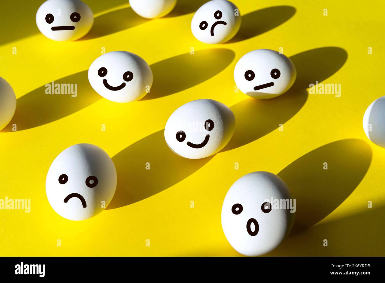 Concept picture about emotionality with happy, unhappy, angry and surprised faces of eggs on yellow background, creativity collage Stock Photo