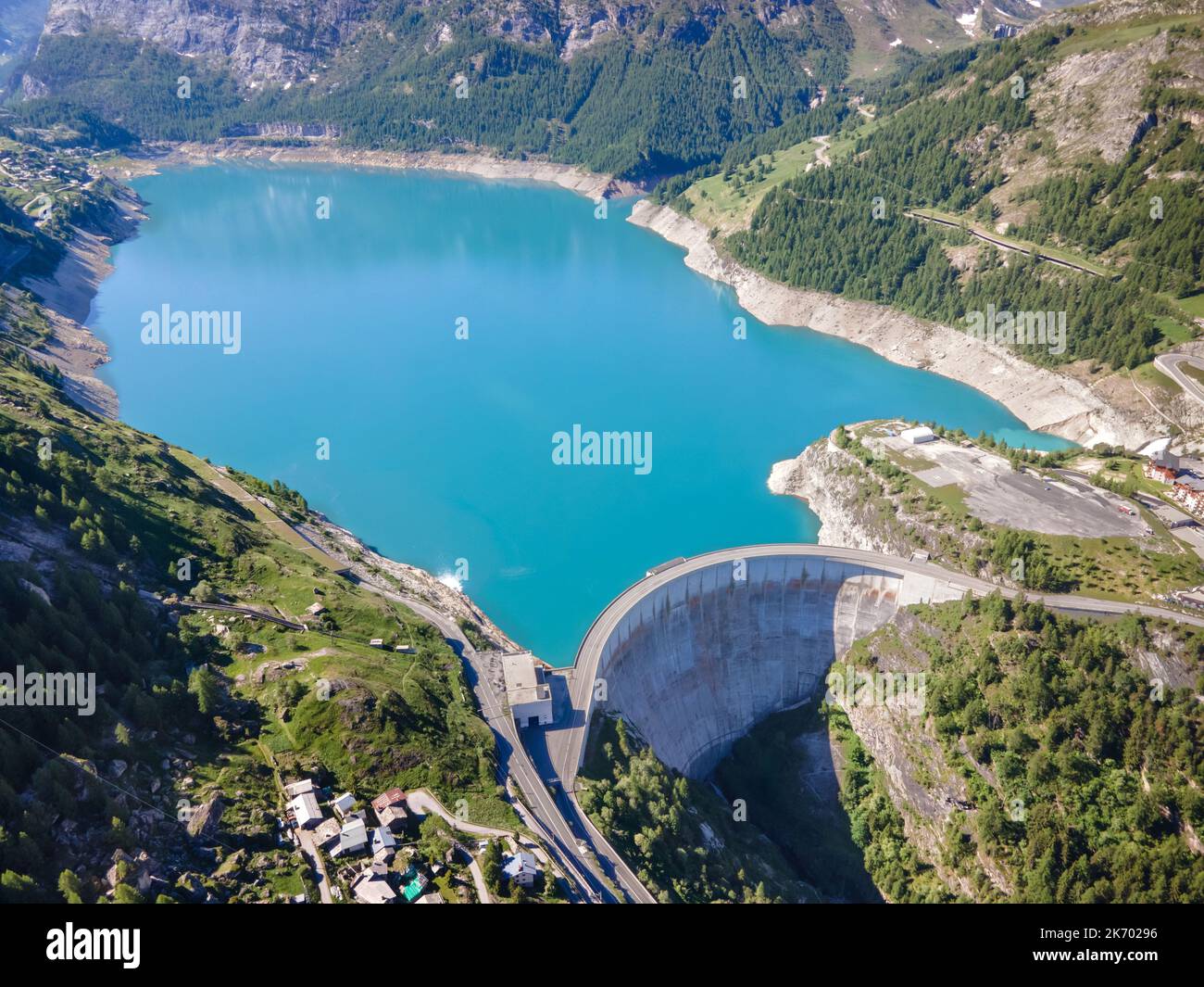 Water dam and blue reservoir lake aerial view in Alps mountains generating hydroelectricity. Low CO2 footprint, decarbonize, renewable energy, sustain Stock Photo