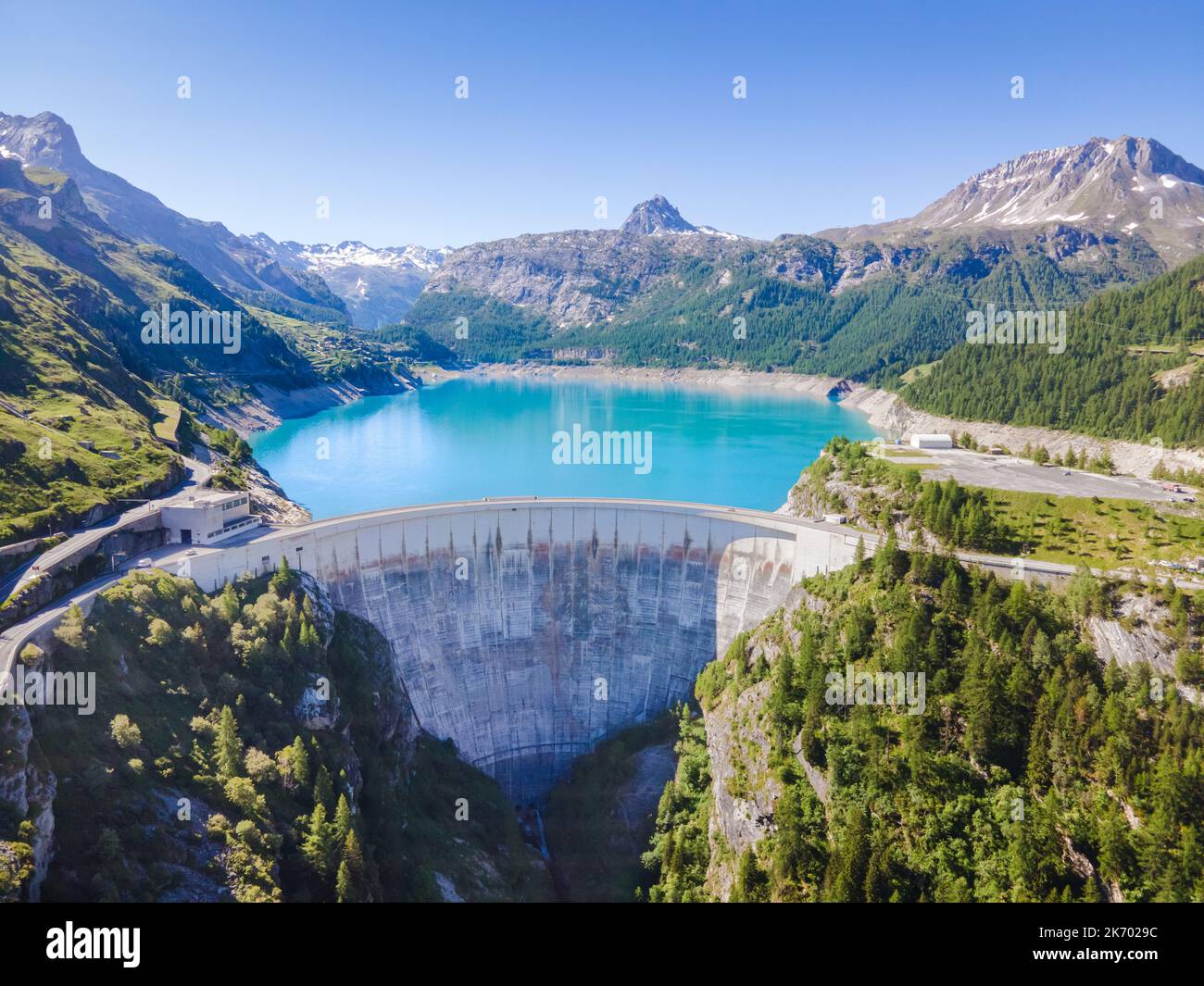 Water dam and reservoir lake aerial view in Alps mountains in summer generating hydroelectricity. Low CO2 footprint, decarbonize, renewable energy, su Stock Photo