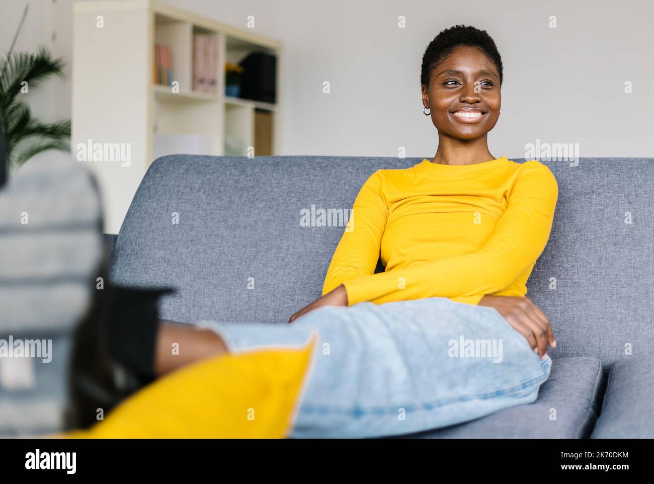 Smiling young african woman relaxing at home sitting on sofa Stock ...