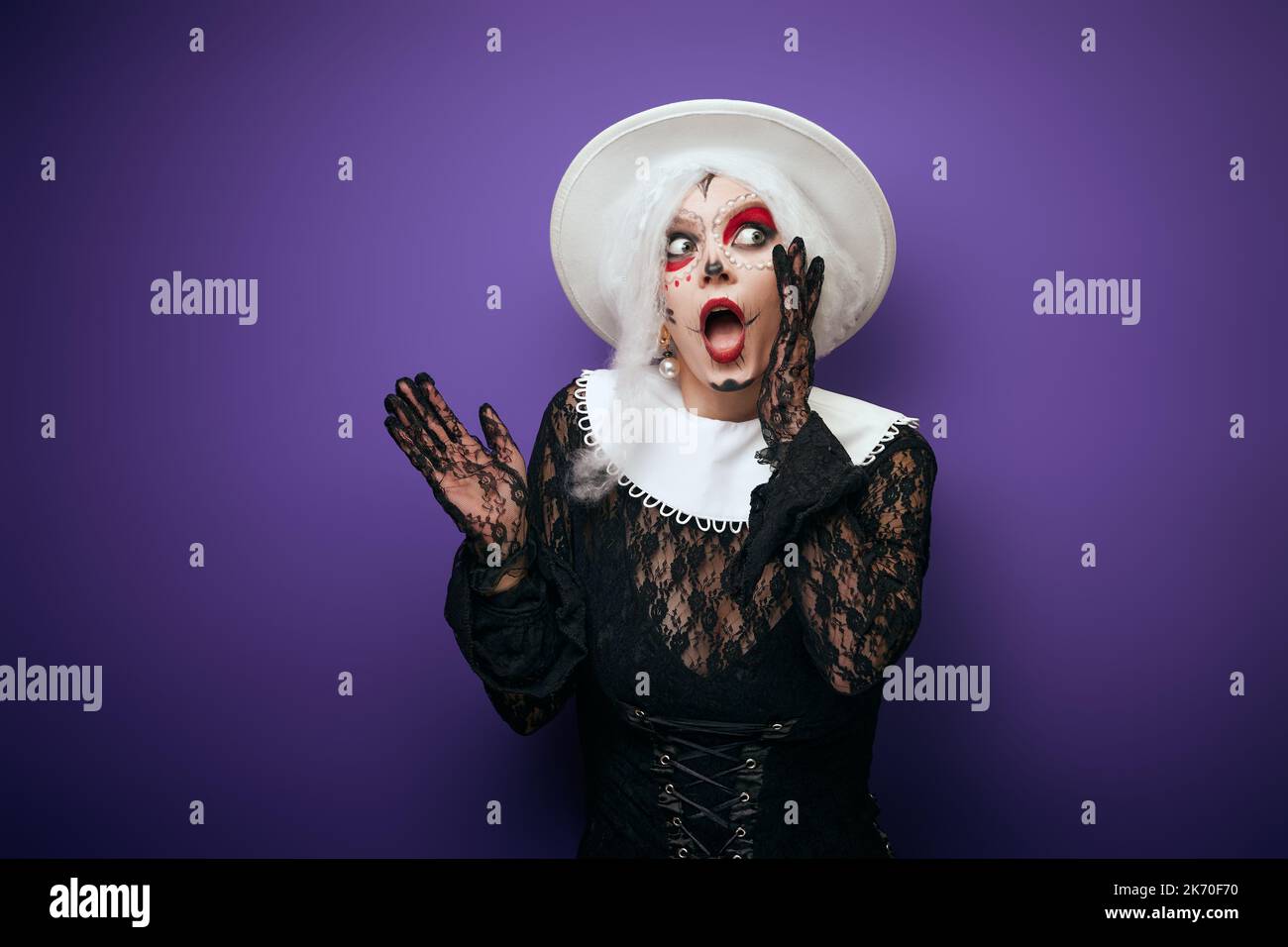 Scared whispering woman with grey hair in Halloween costume Stock Photo