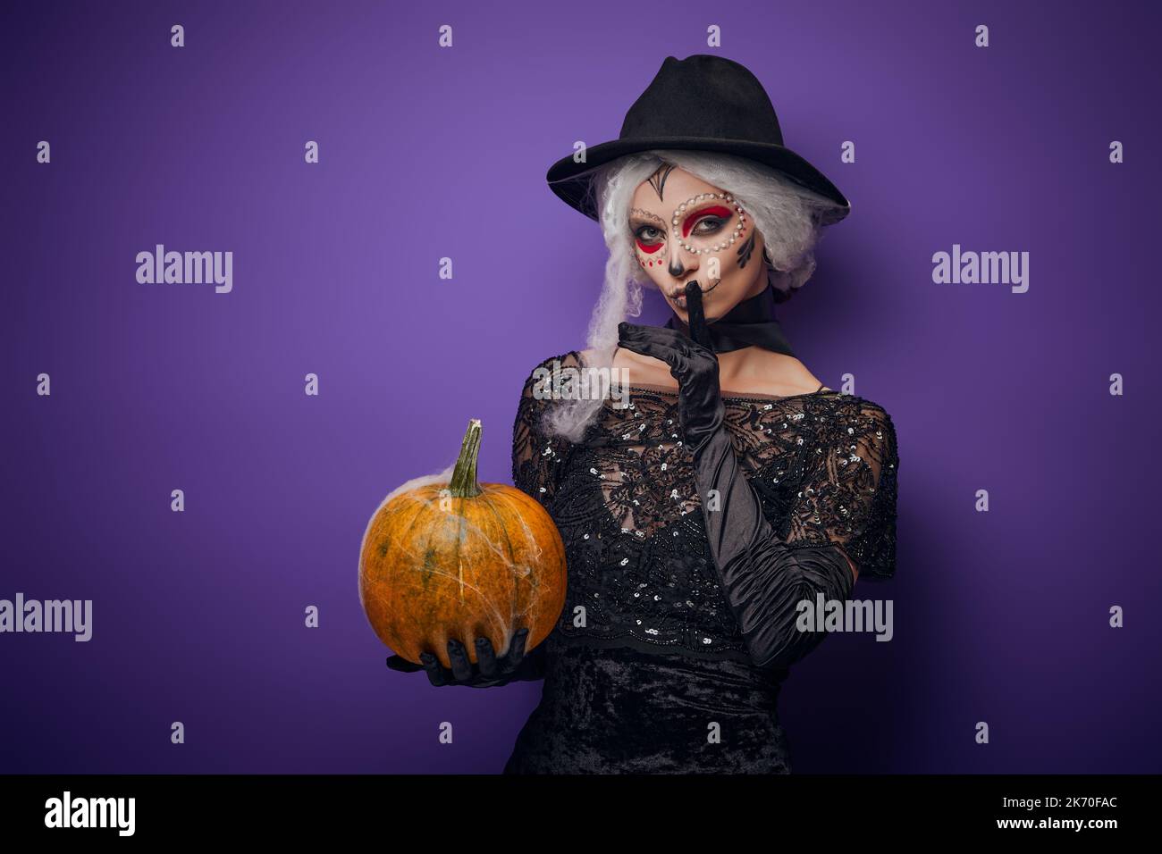 Witch with grey hair whispering in Halloween costume Stock Photo