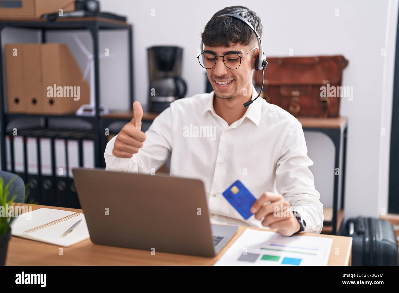 Young hispanic man working using computer laptop holding credit card ...