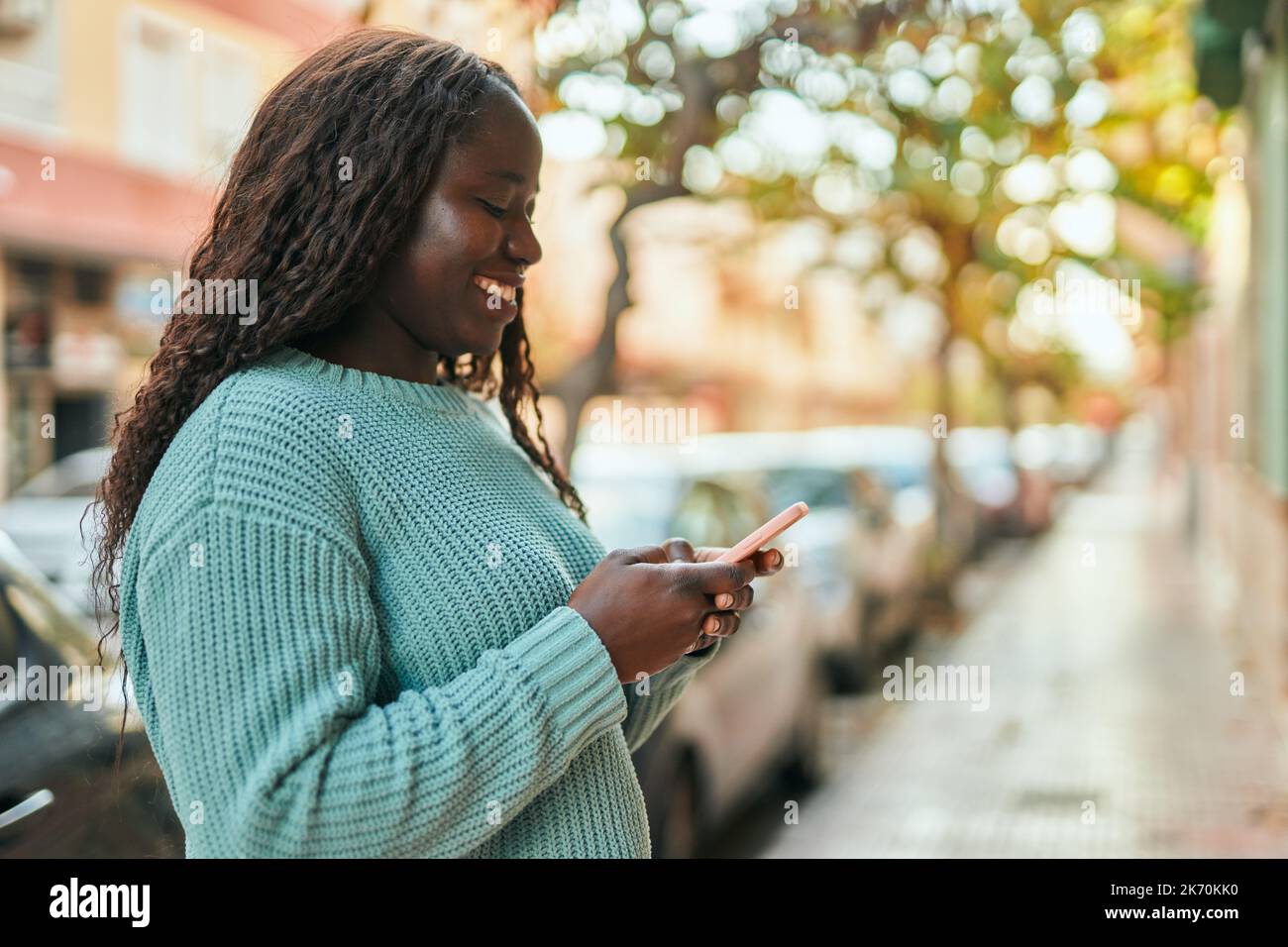 Young african woman smiling happy using smartphone at the city Stock ...