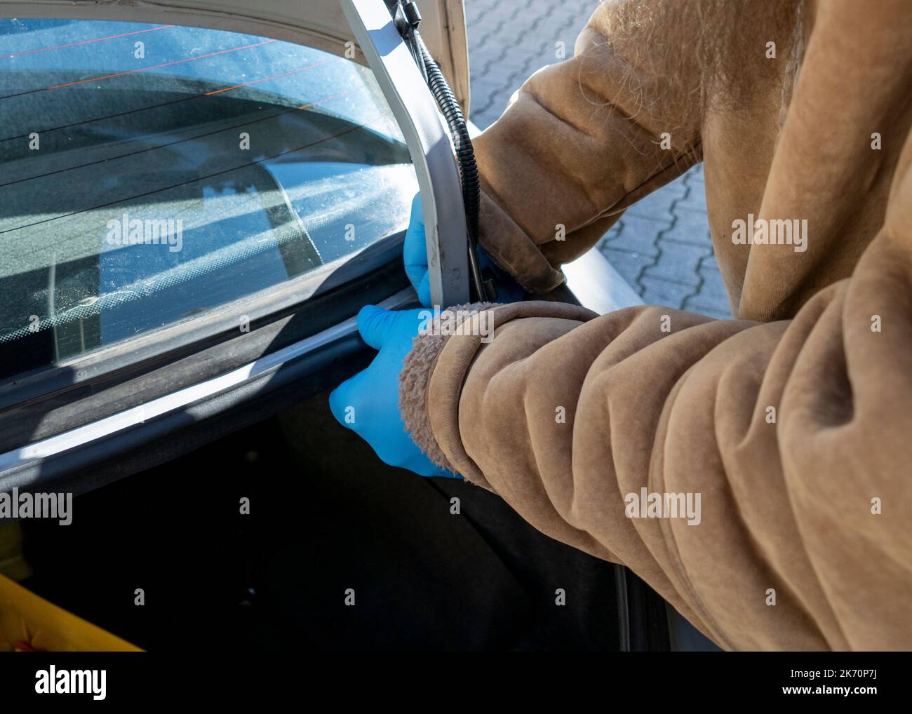 Mann repariert die Dichtung am Kofferraum eines Autos Stock Photo