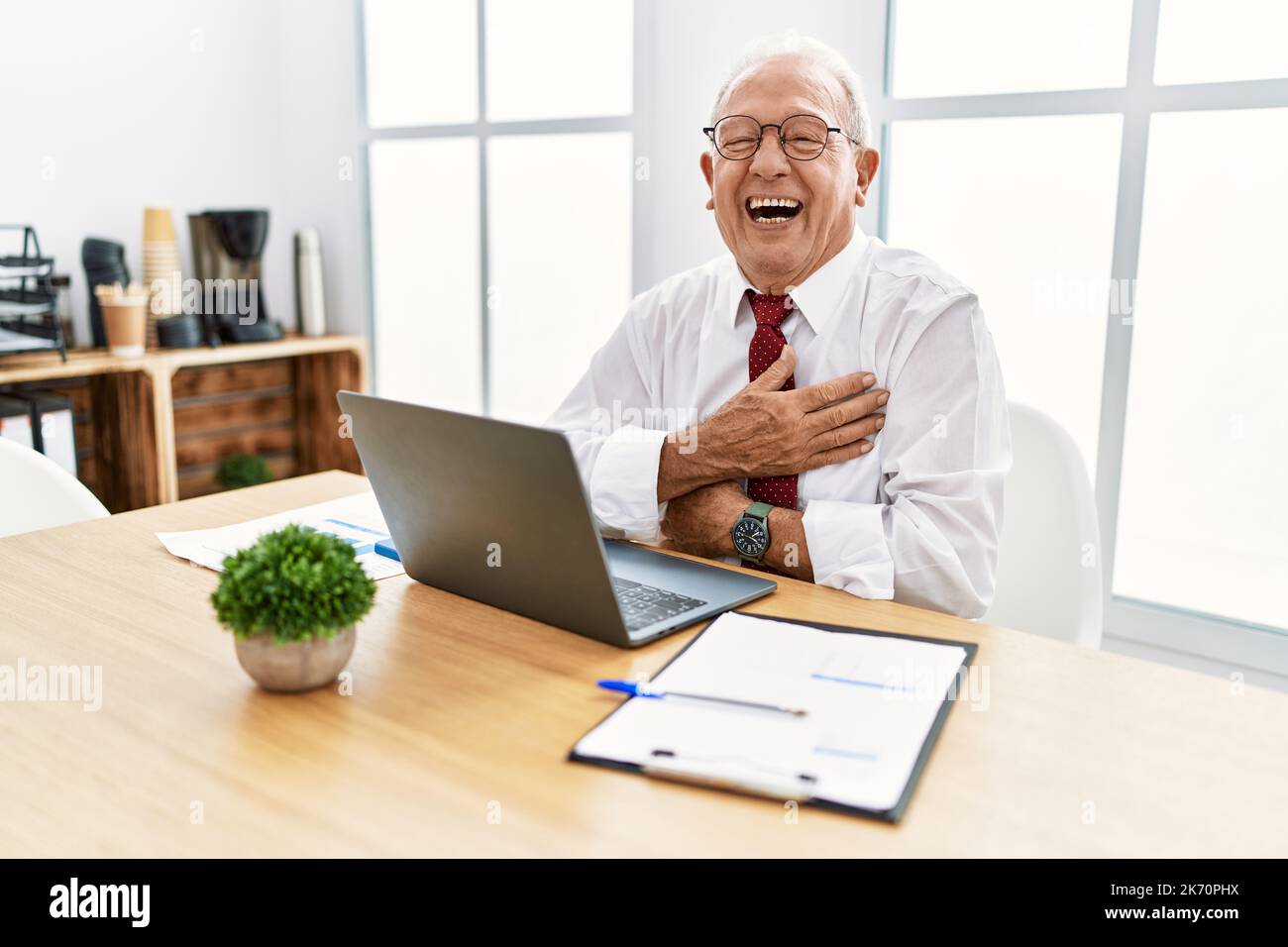 Senior man working at the office using computer laptop smiling and ...